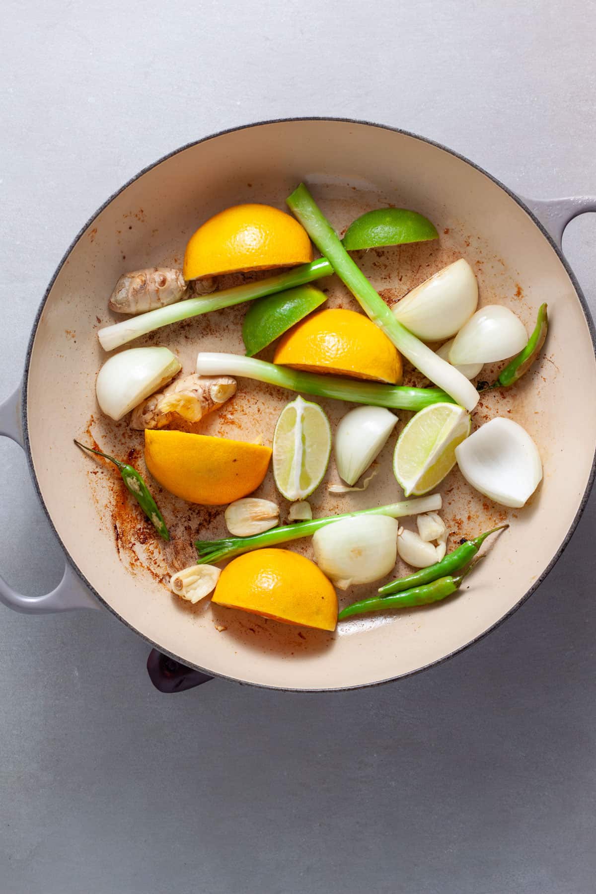 Scallions, citrus, ginger, onion and garlic in a skillet cooking.
