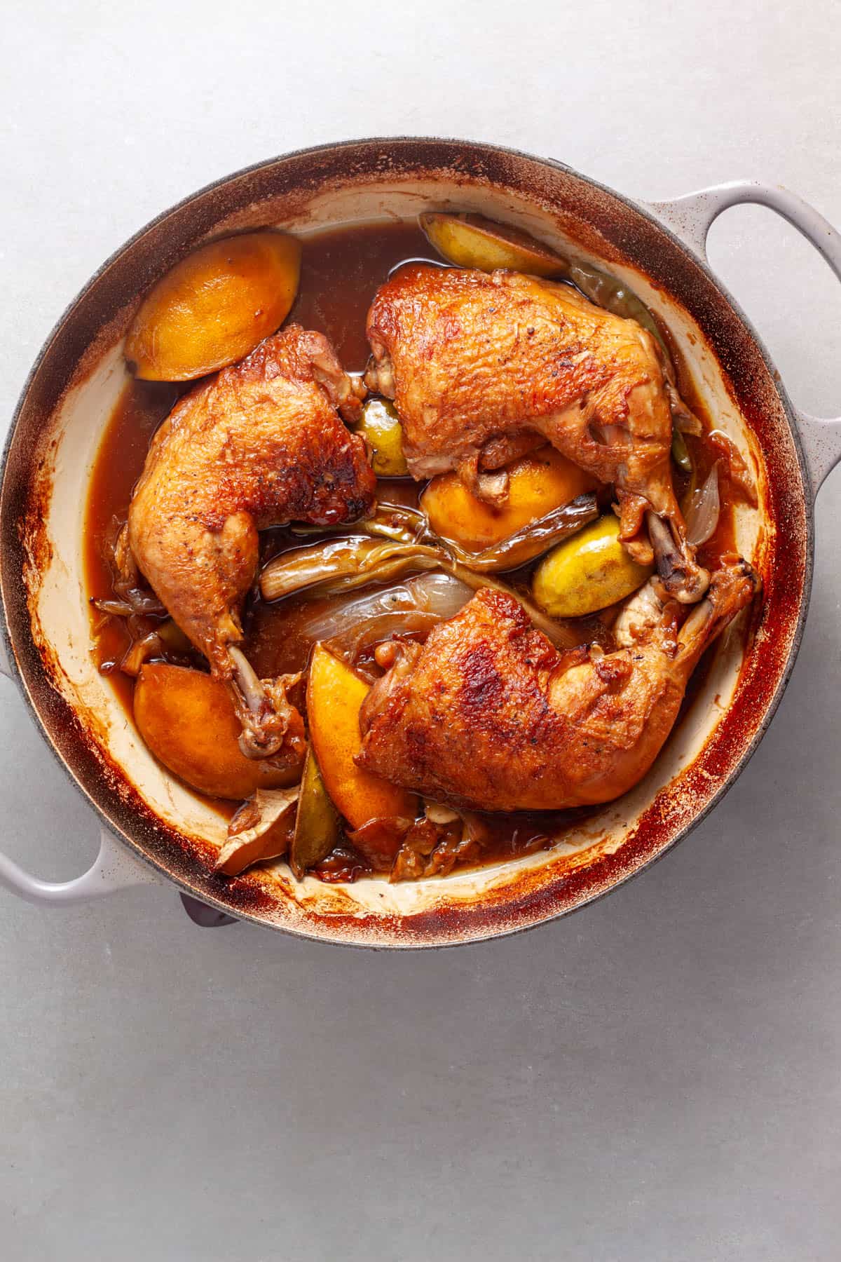 Chicken leg quarters added to a skillet with aromatics for a spicy chicken with ginger, citrus and soy.
