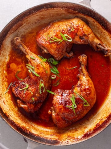 Chicken leg quarters smothered in a spicy ginger, citrus and soy sauce in a large skillet.