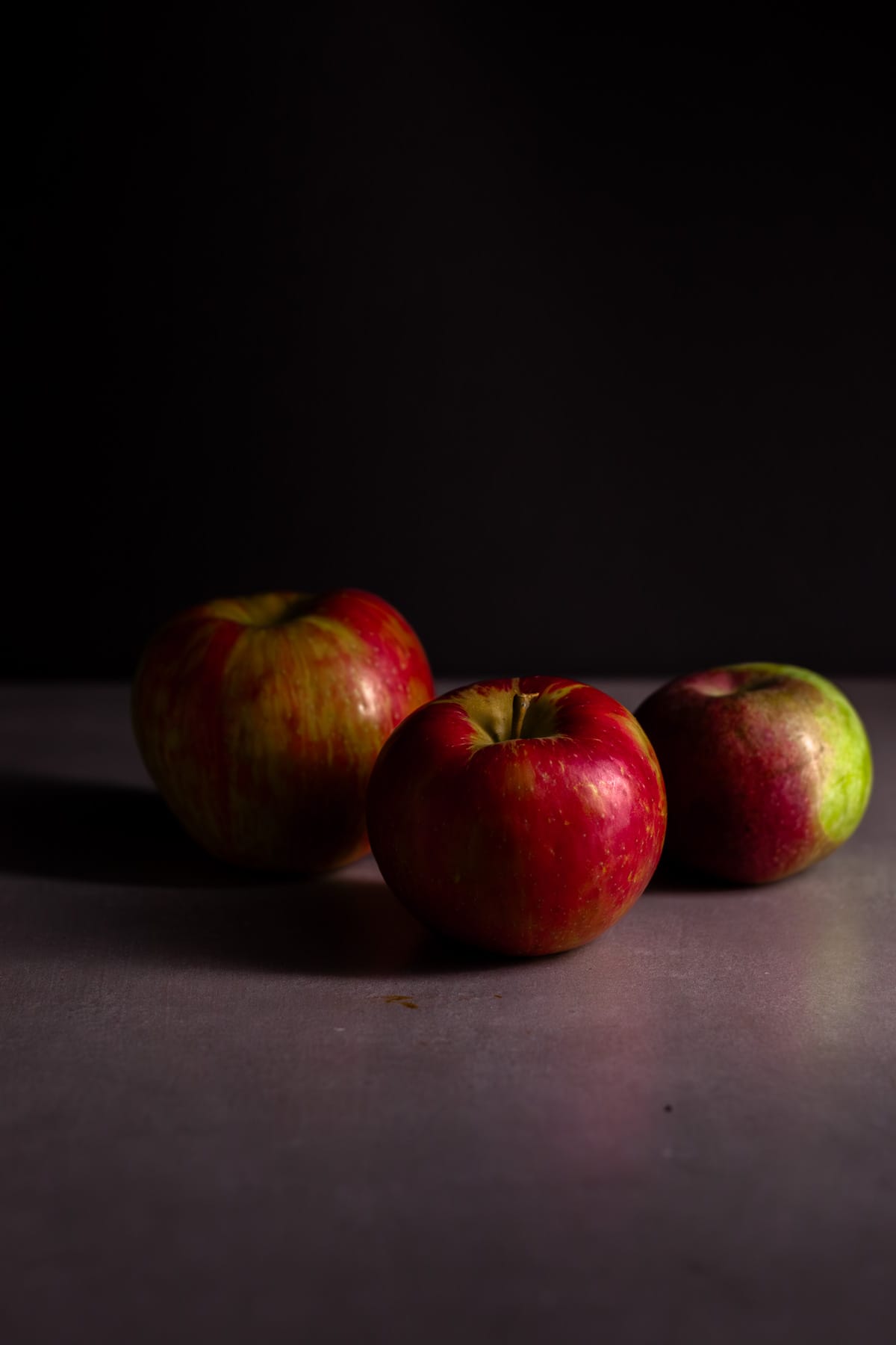Apples on a gray table with a dark background.