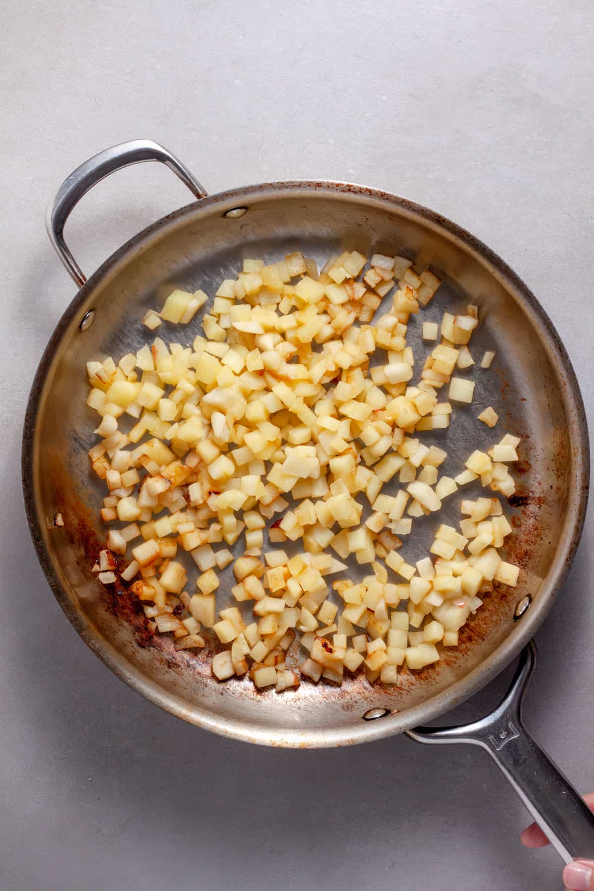 Finely diced apples sautéing in a large skillet in butter.