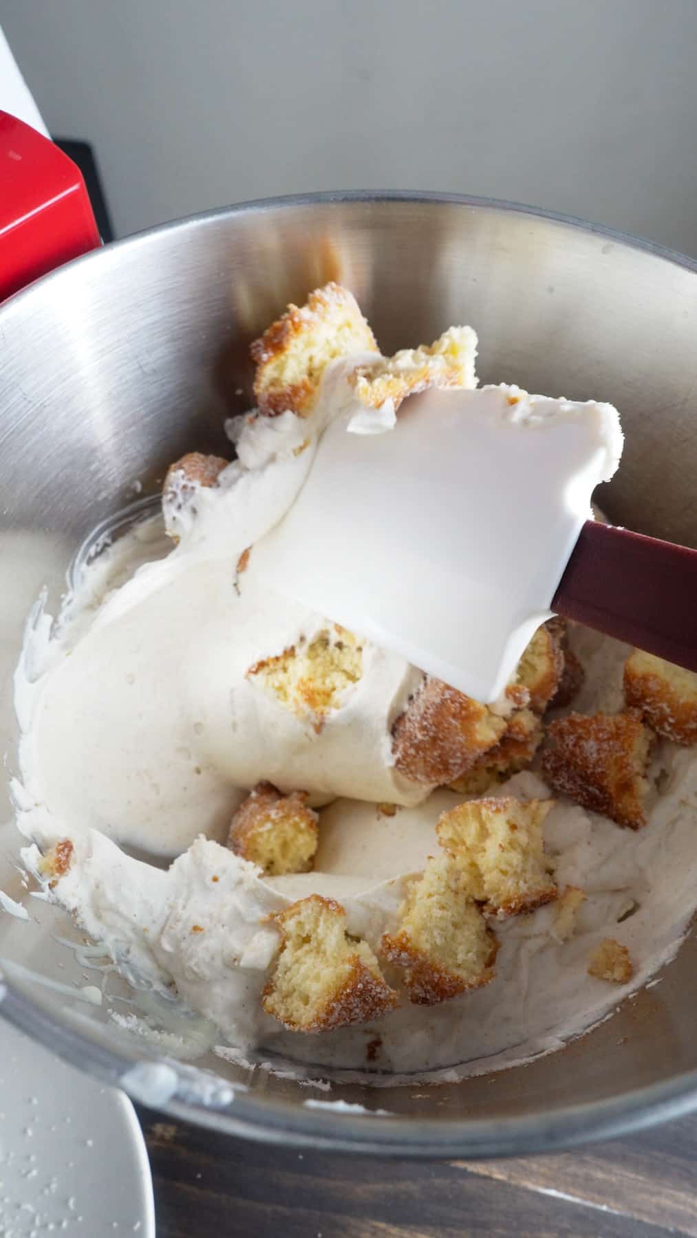 Cider donuts torn into bite size pieces getting stirred into no-churn ice cream base.
