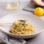 A bowl of lemon caper pasta topped with fresh parsley.