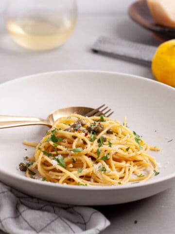 A bowl of lemon caper pasta topped with fresh parsley.