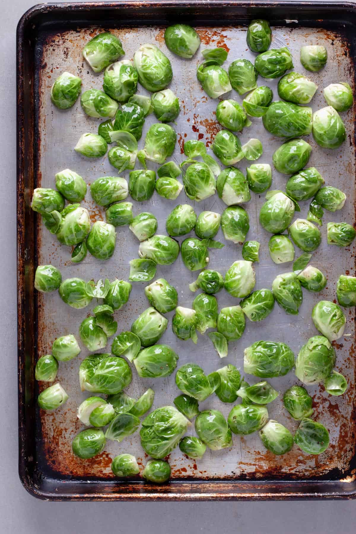 Halved Brussels sprouts on a baking sheet getting ready to roast.
