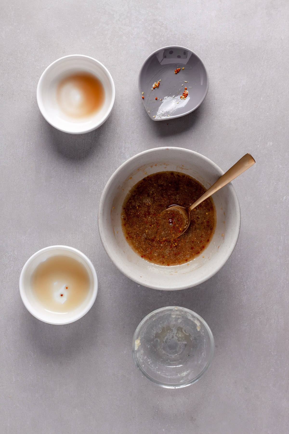 A sauce of mustard, maple, balsamic and melted butter getting stirred in a small bowl.