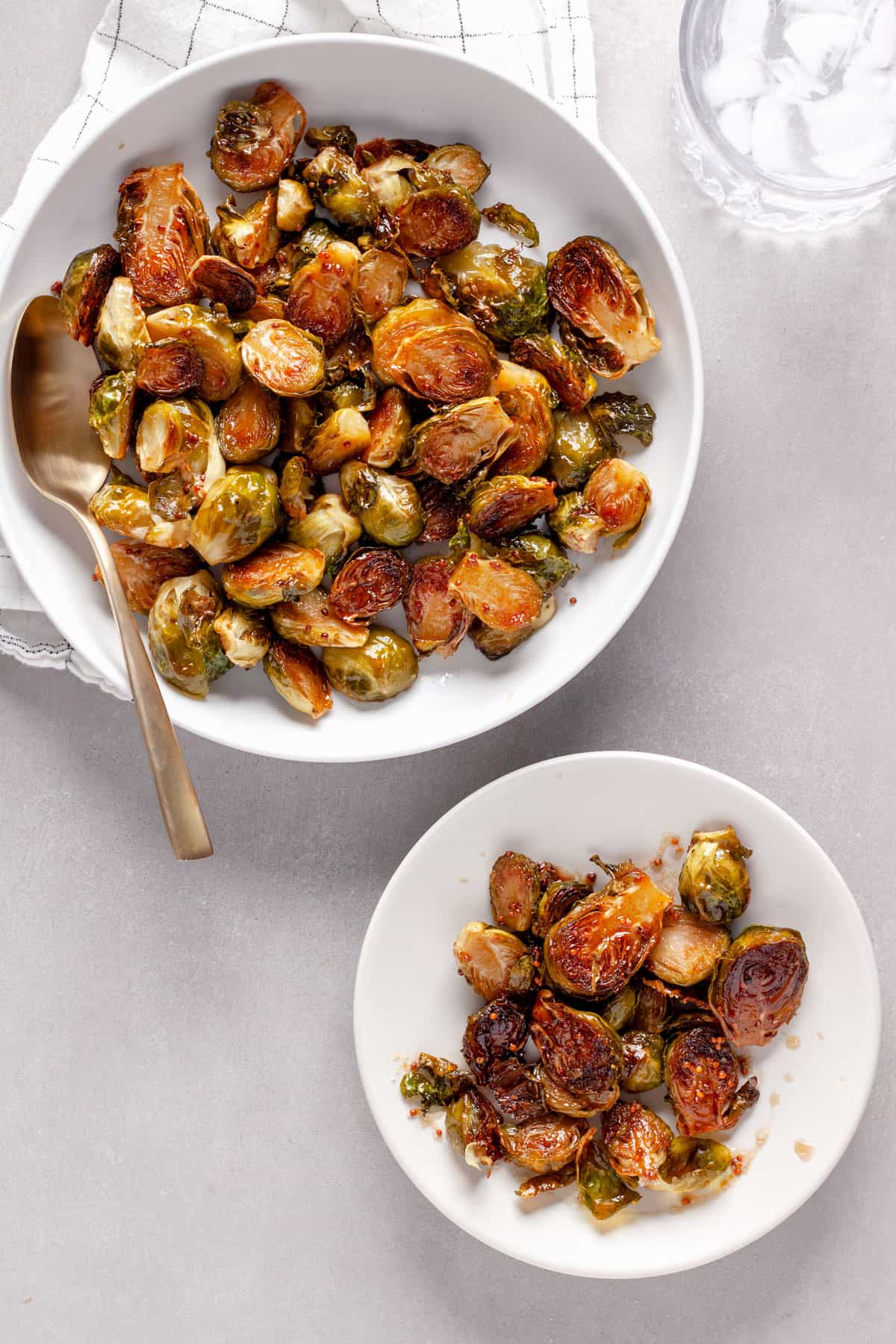 A large bowl of maple balsamic brussels sprouts with a small plate to the side.