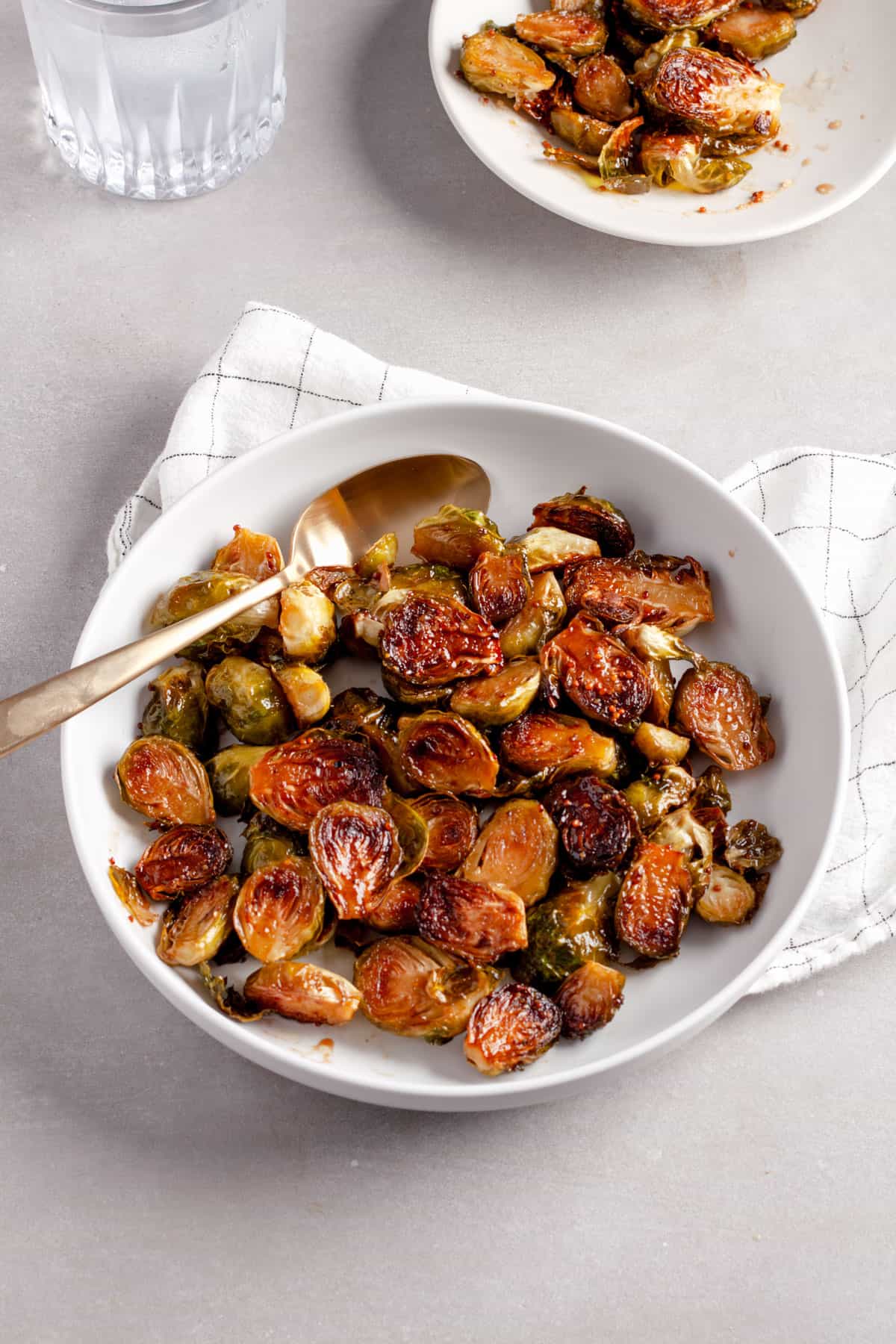 A serving platter of maple balsamic Brussels sprouts with a small bowl in the background.