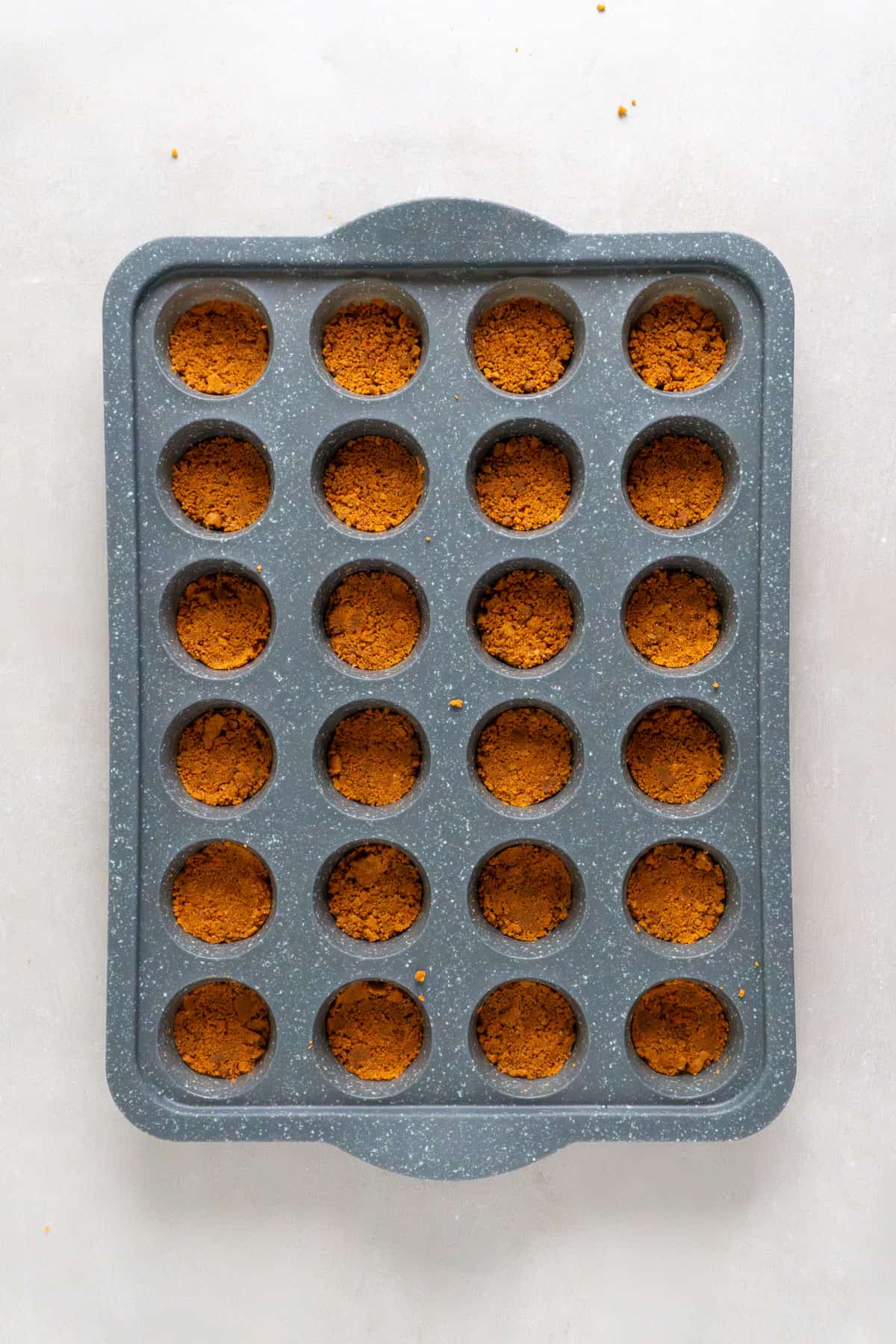 Biscoff cookie crust pressed into a mini muffin pan.