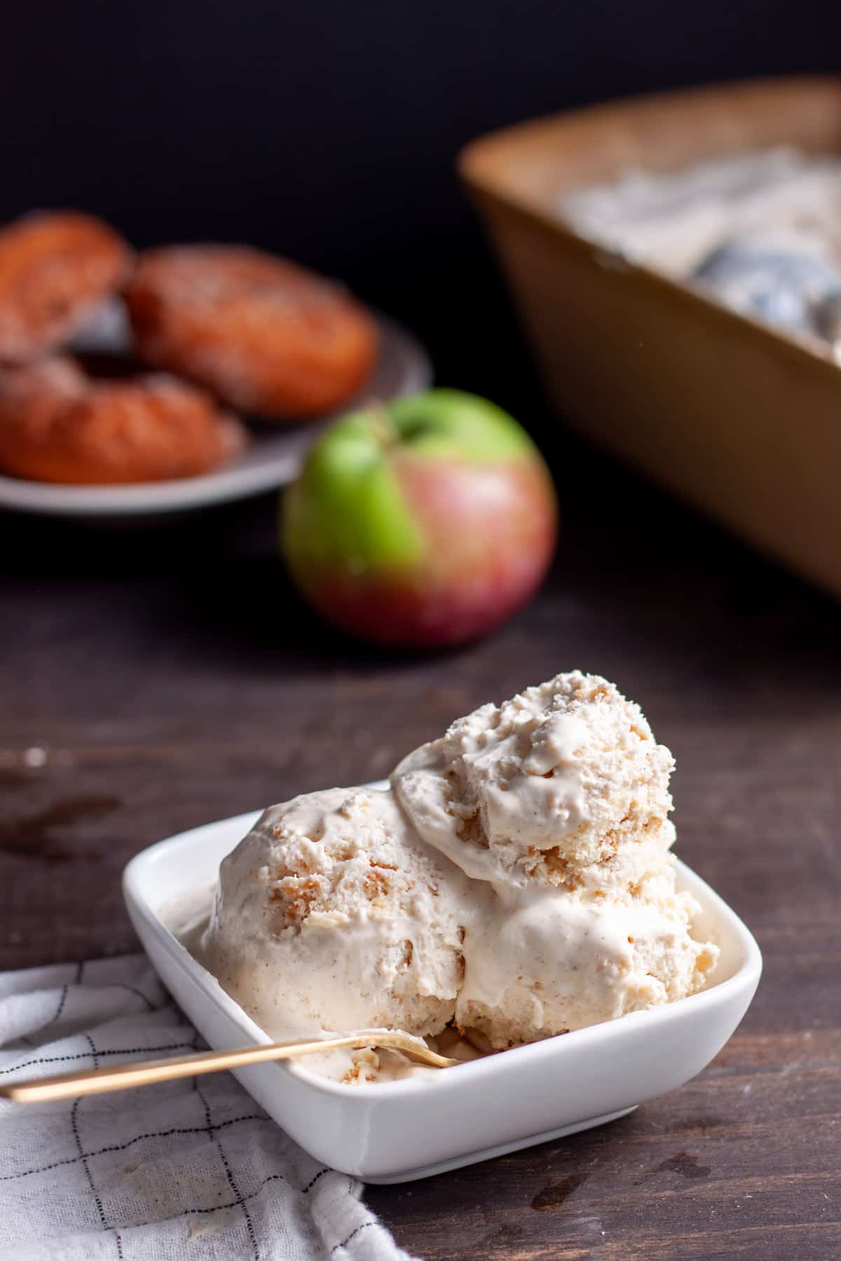 A small bowl of cider donut ice cream with donuts in the background.