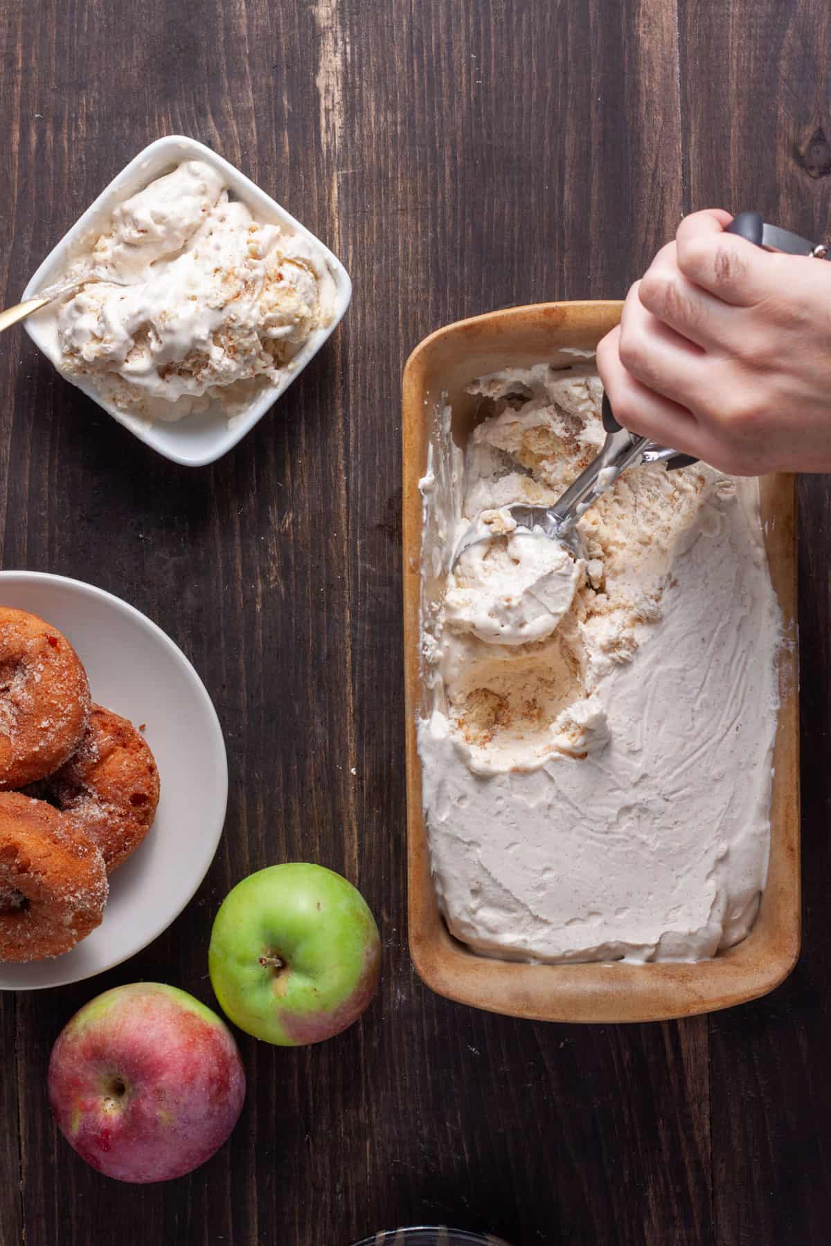 Cider Donut Ice Cream in a loaf pan getting scooped out and served in small dishes.
