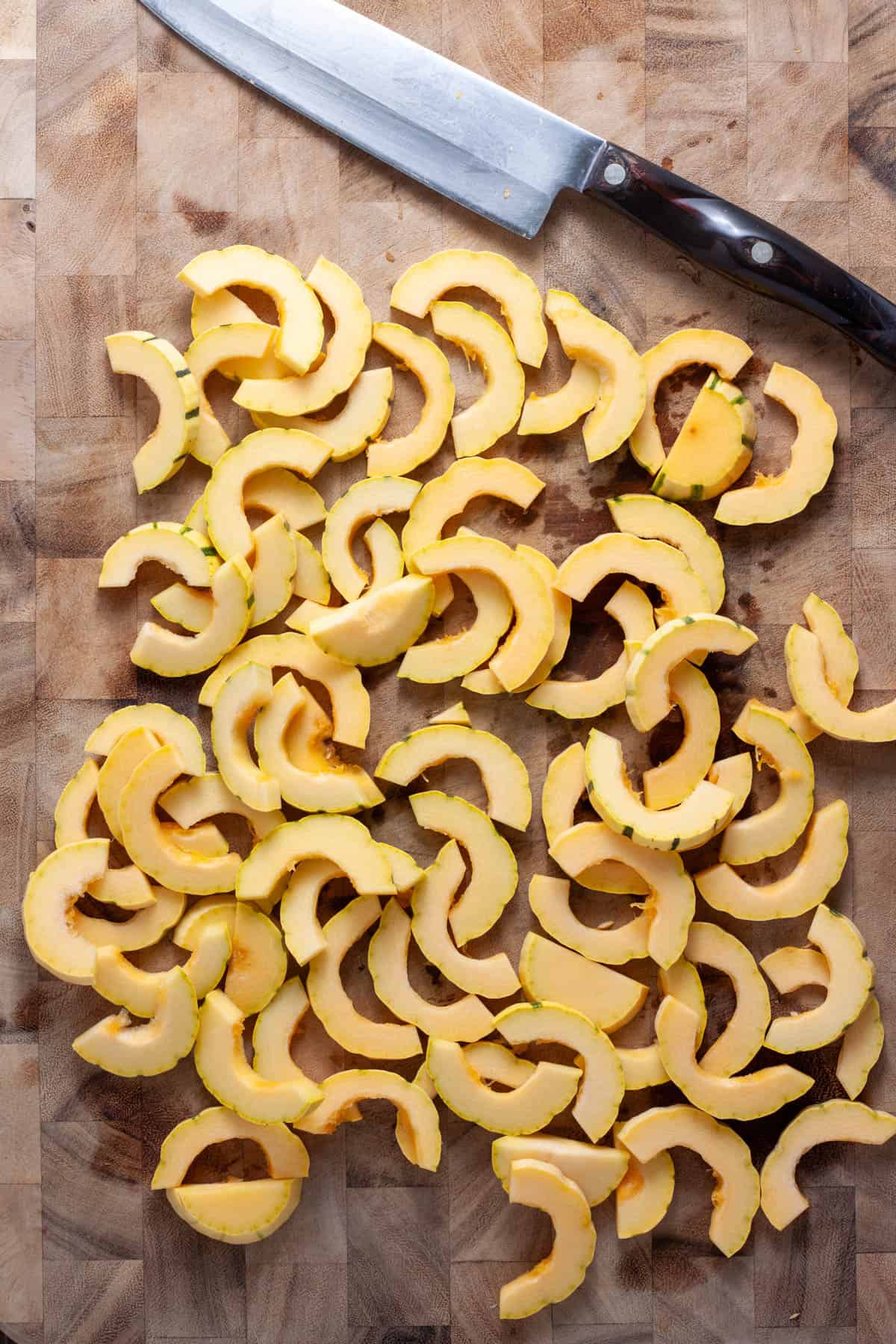 Thinly sliced delicata squash on a cutting board.