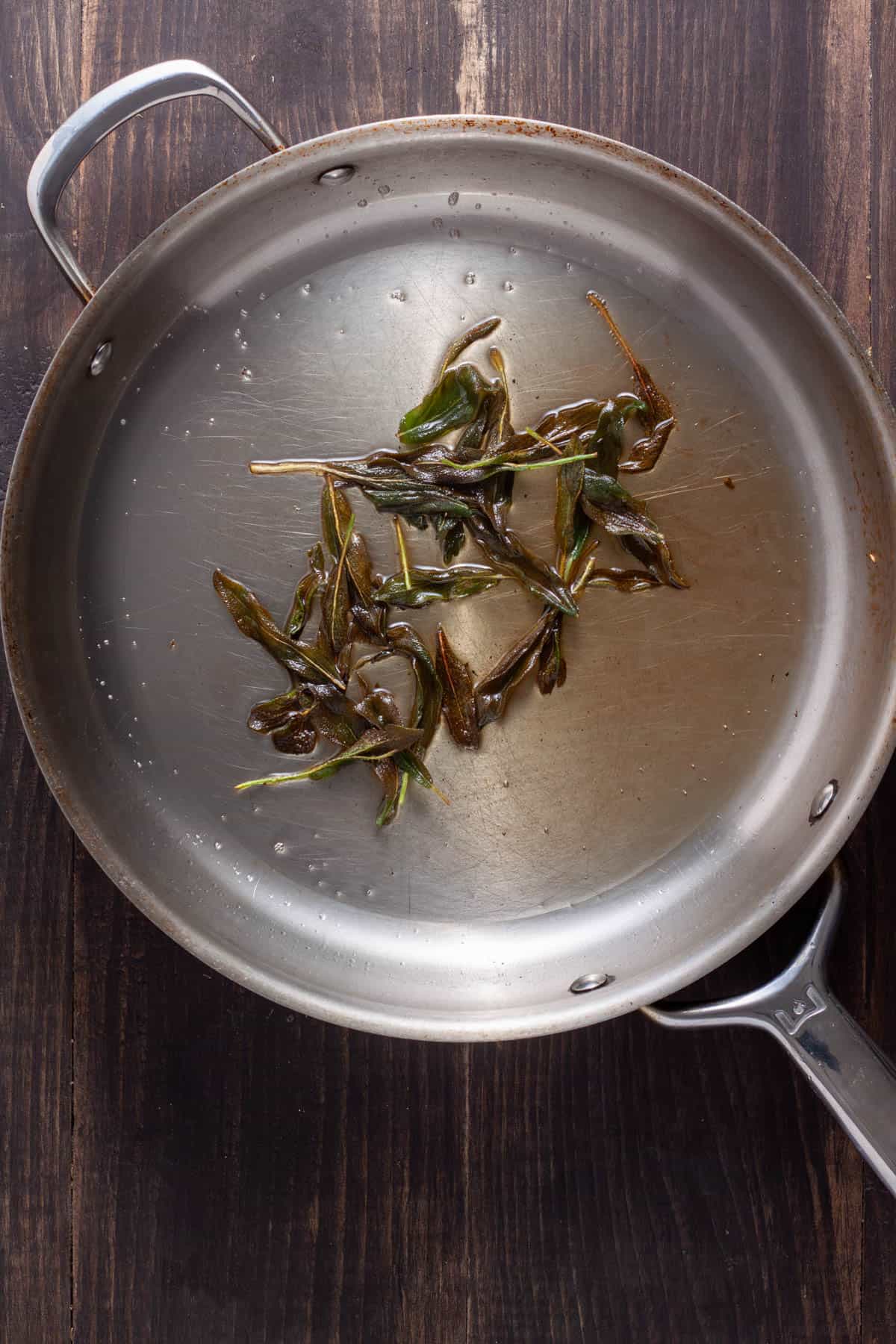 Sage frying in a large skillet with oil and butter.