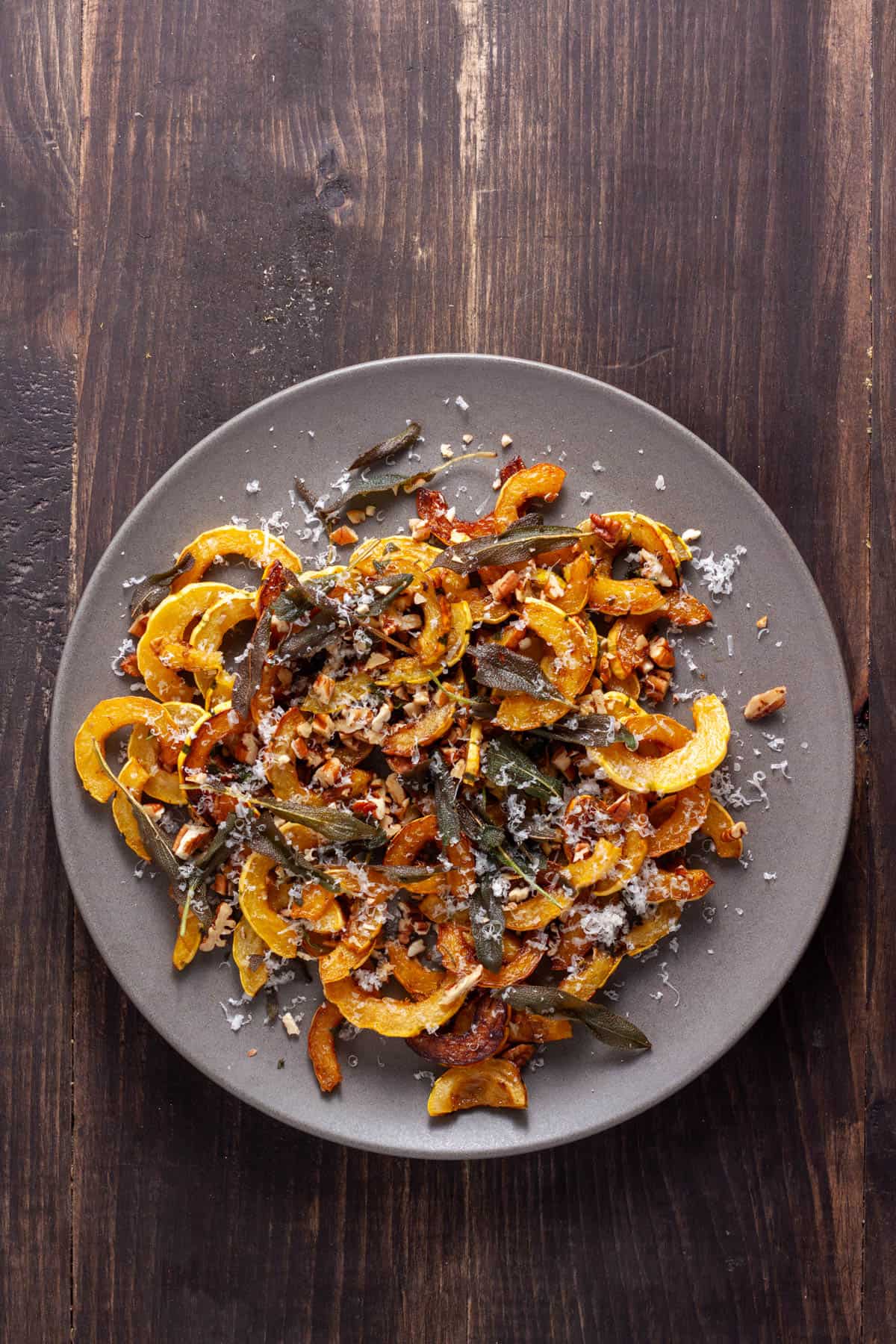 Sauteed delicata squash topped with crispy sage on a serving platter. 