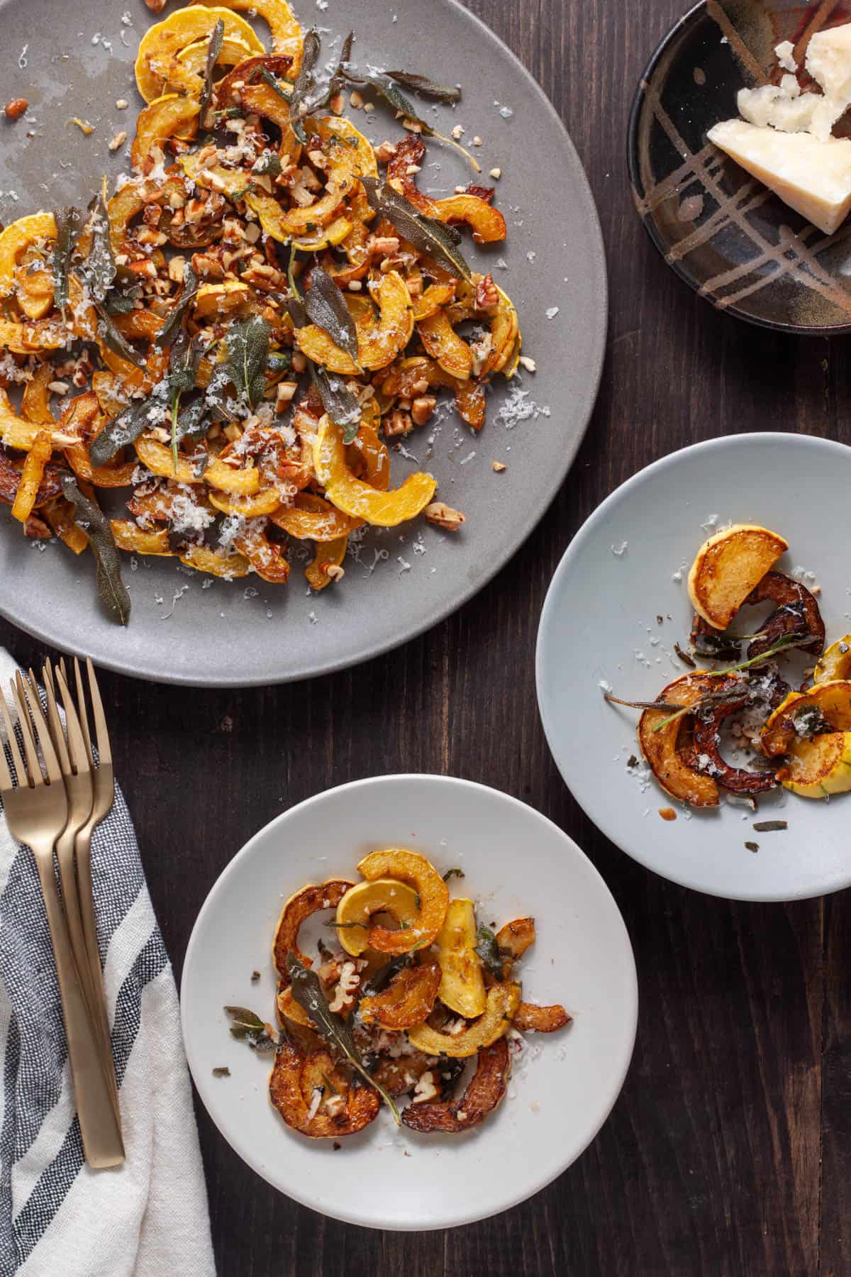 Sauteed Delicata Squash with crispy sage on a couple small plates and a large plater to the side.