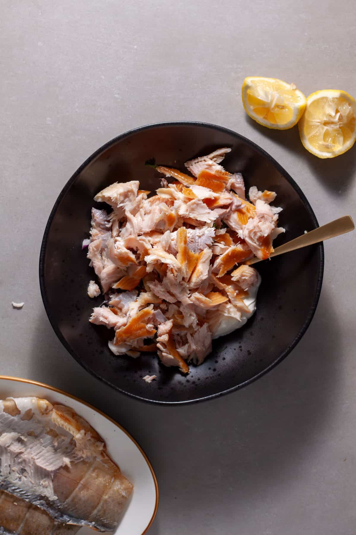 Shredded smoked trout added to a mixing bowl for a smoked trout salad.