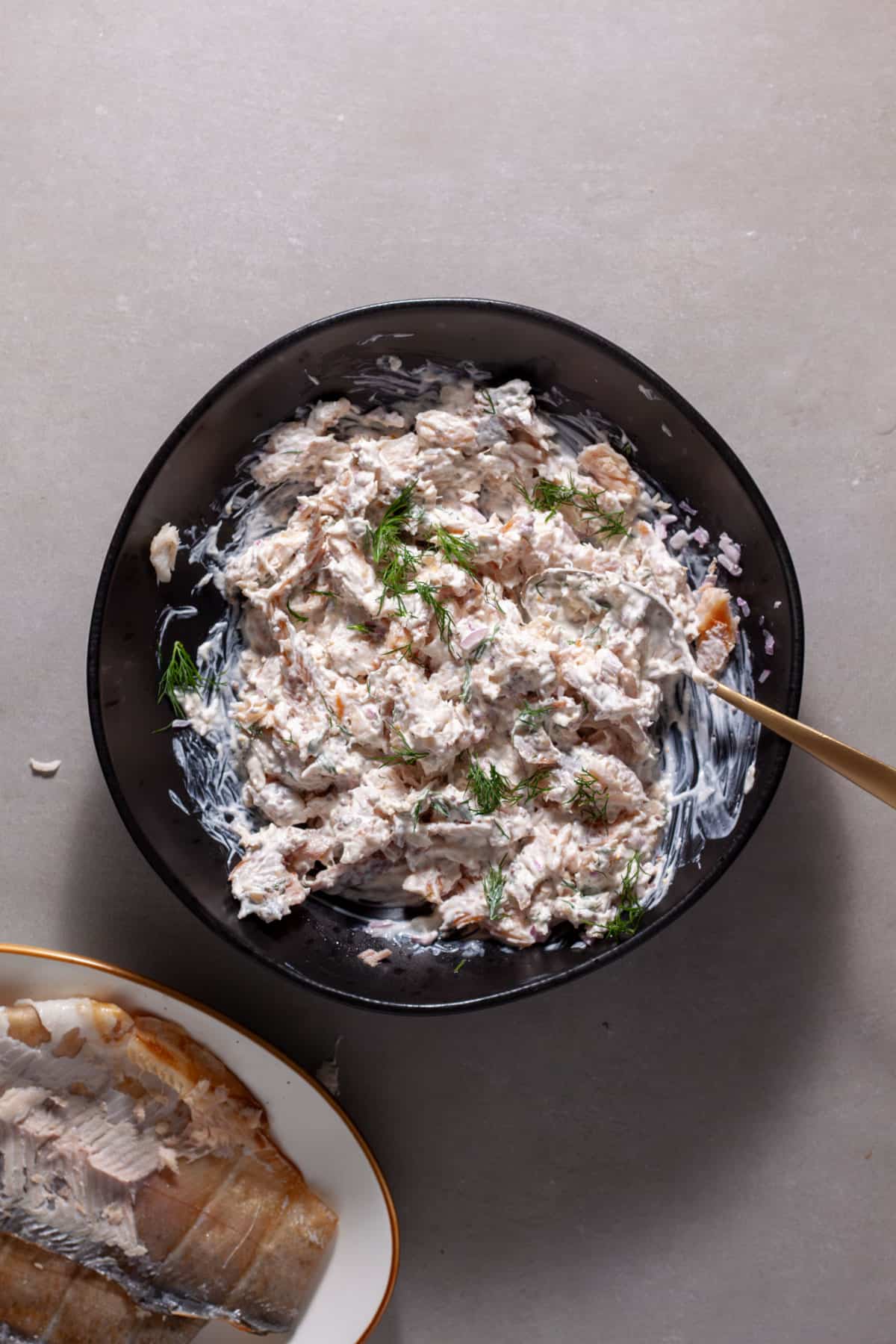 Smoked trout salad mixing together in a black bowl.