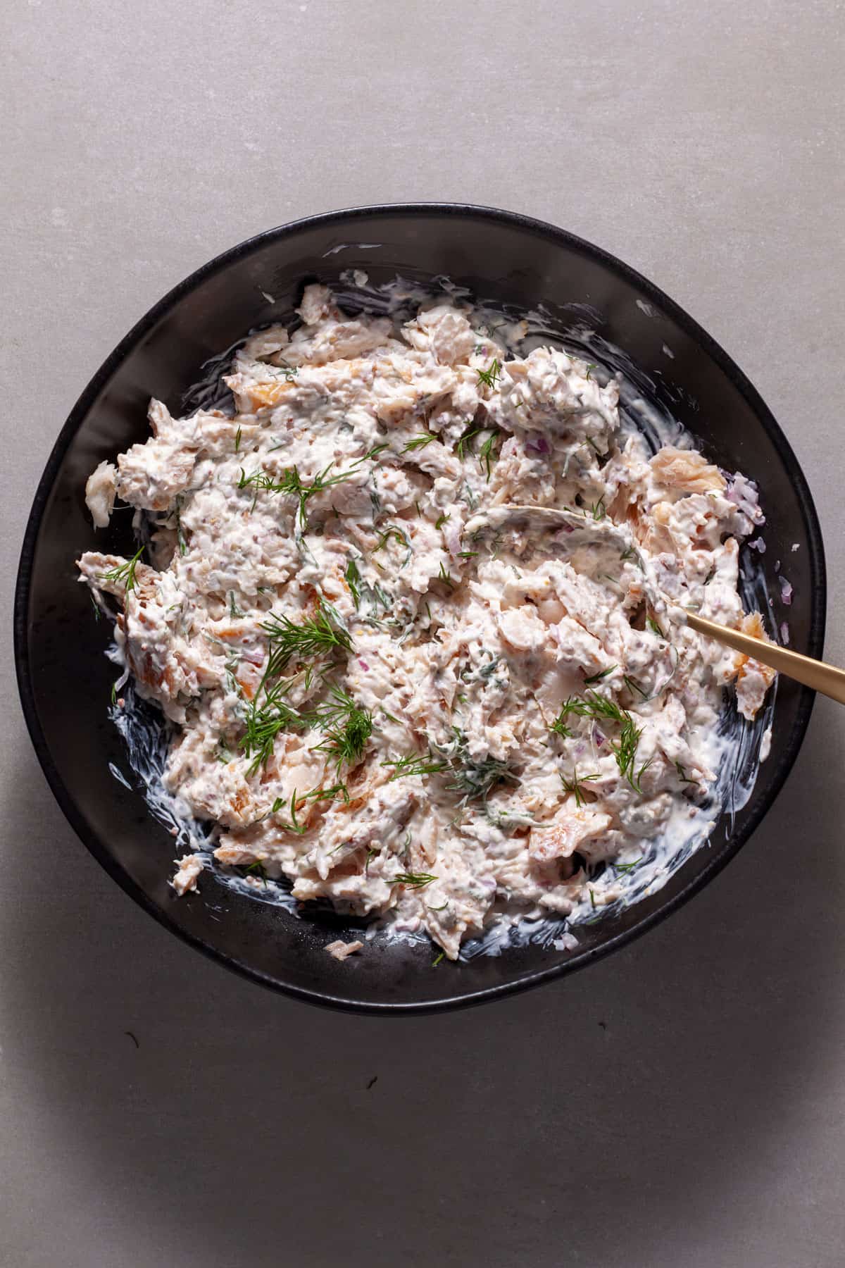 Smoked trout salad mixing together in a black bowl.
