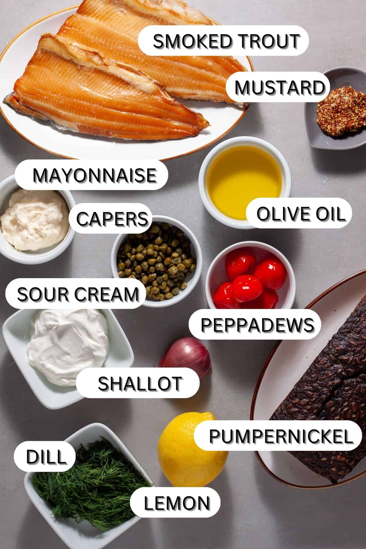 Ingredients for a smoked trout tartine with crispy capers on a gray table.
