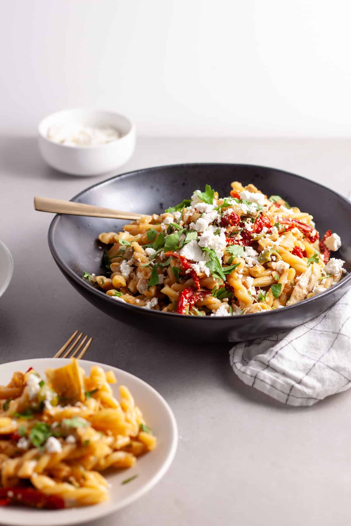 Sun-dried tomatoes and artichoke pasta in a black serving bowl.