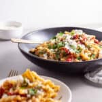 Sun-dried tomato and artichoke pasta in a black serving bowl topped with ricotta salata and parsley.