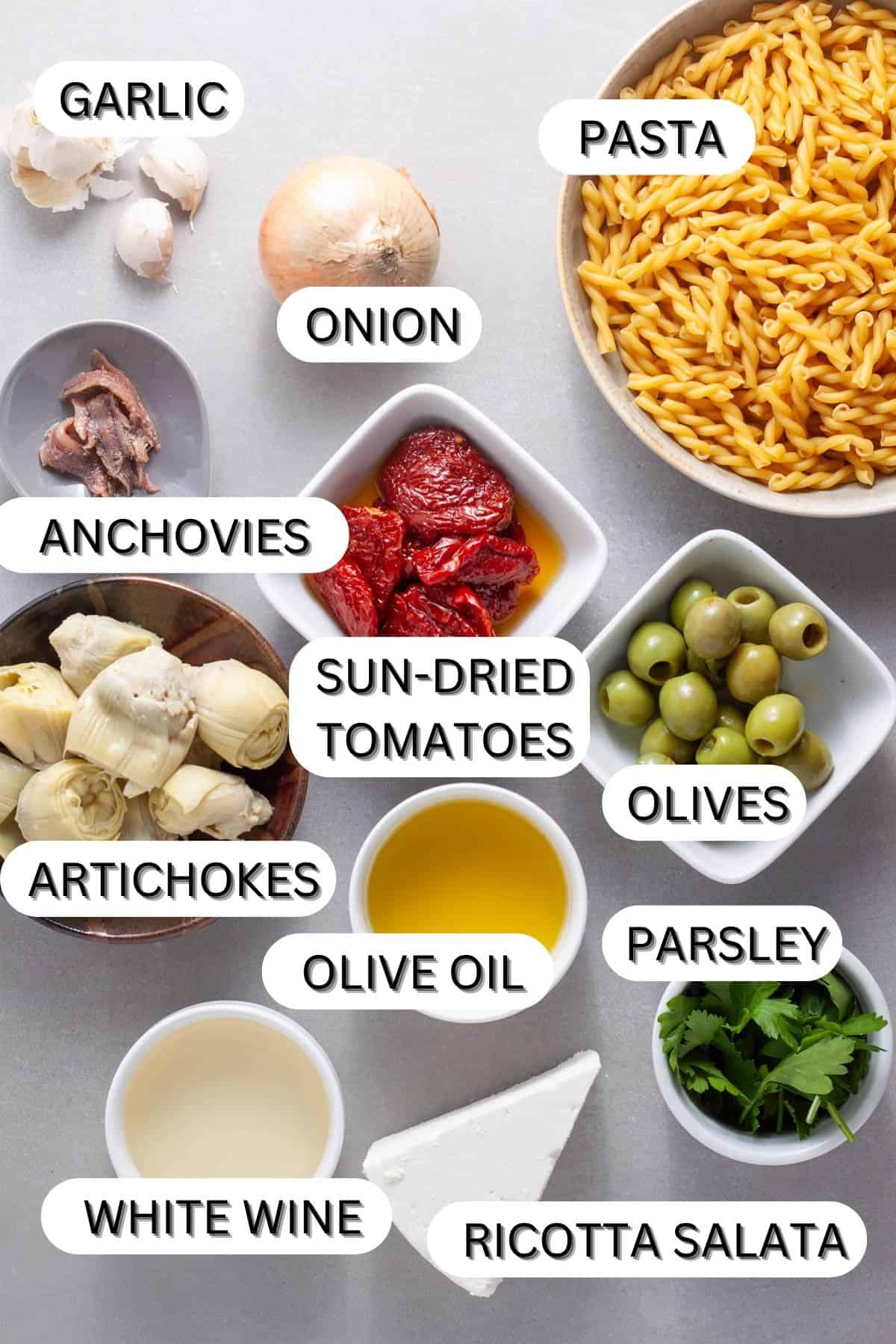 Ingredients for sun-dried tomato and artichoke pasta on a gray table.