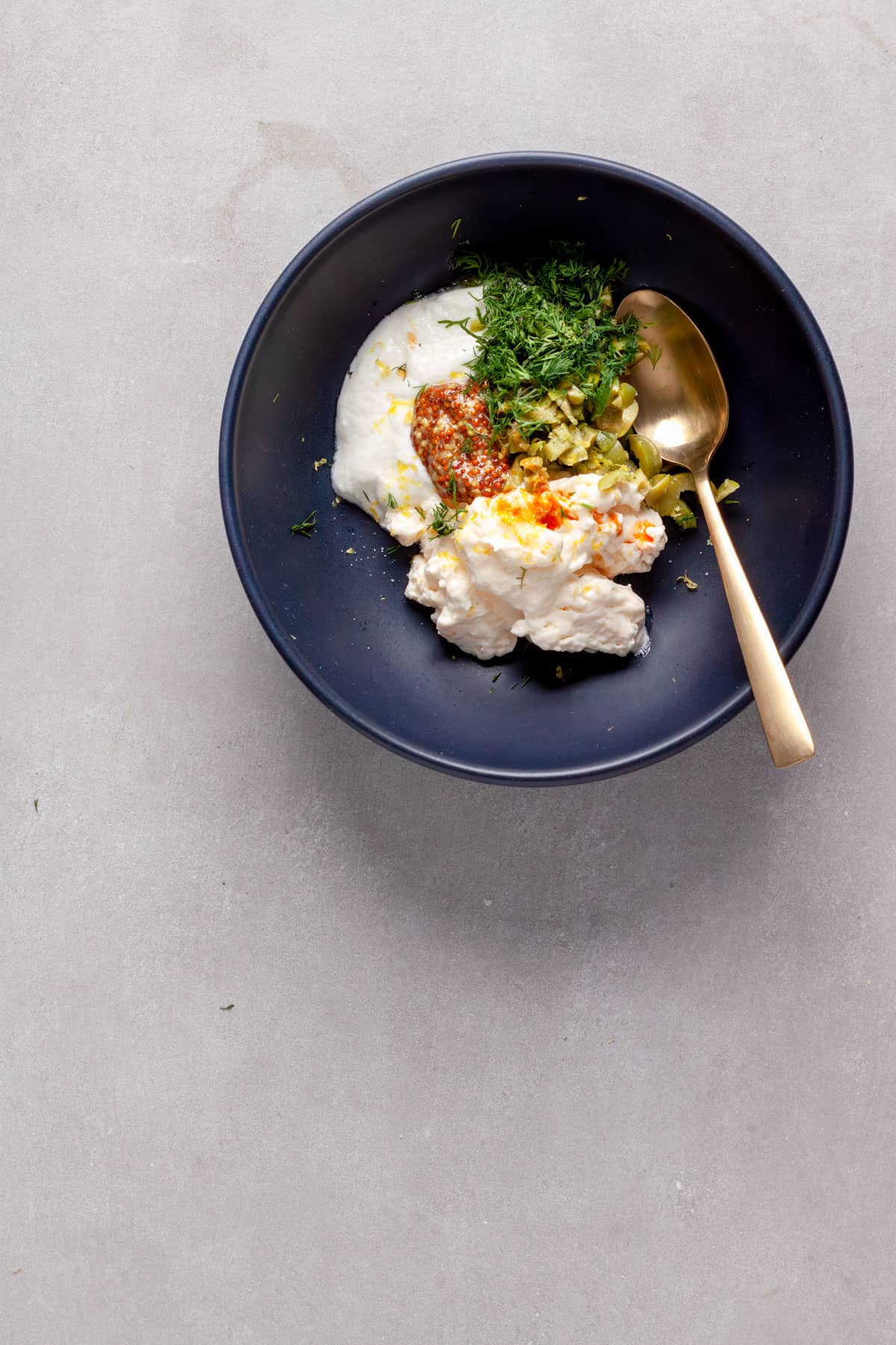 A homemade tartar sauce waiting to get stirred in a medium blue blowl.