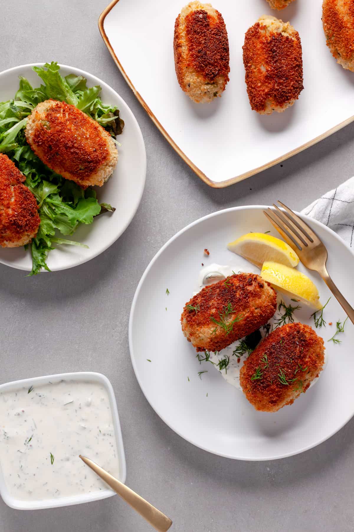 Tuna croquettes on plates with lettuce on one and homemade tartar sauce on another.