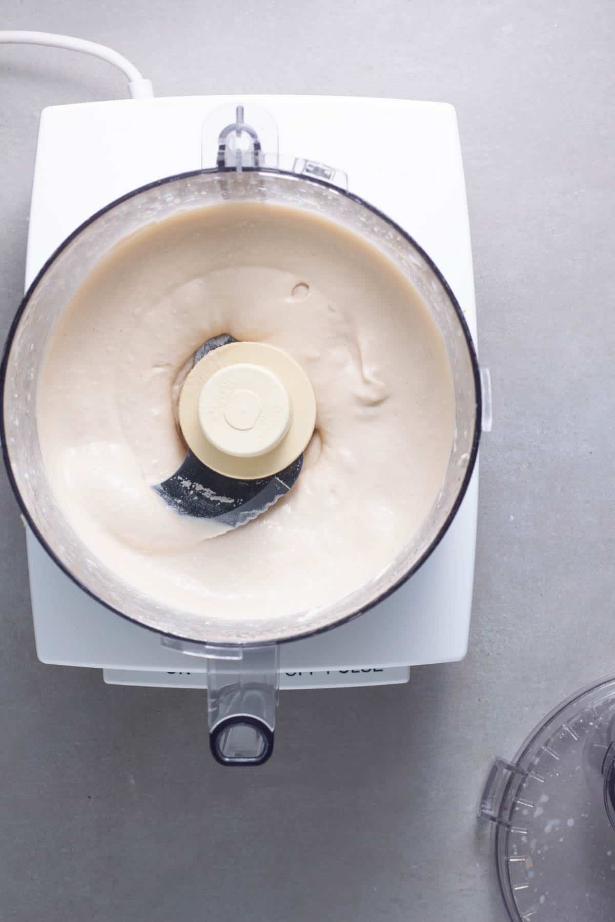 A white bean and tahini dressing mixed together smooth in a food processor.