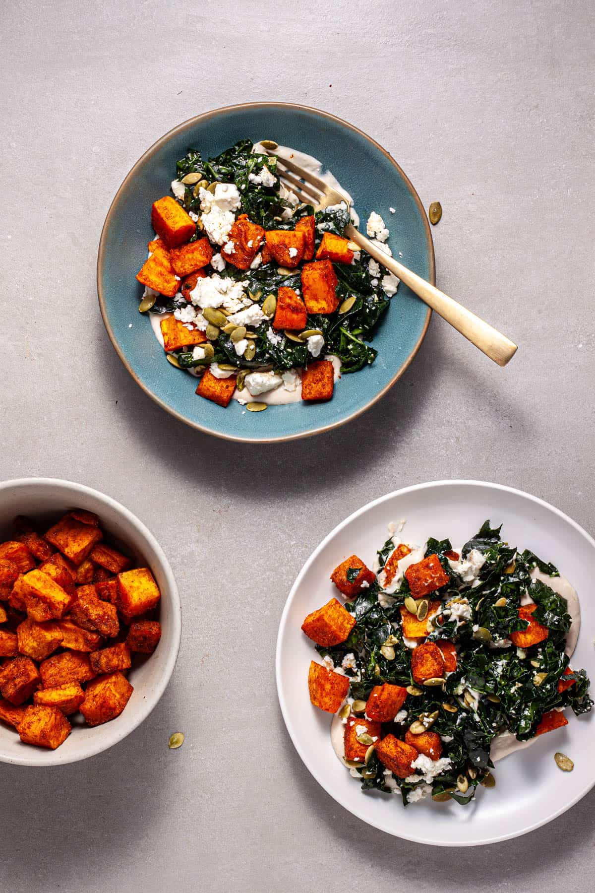 A serving of butternut squash and feta salad on a blue plate and a white plate.
