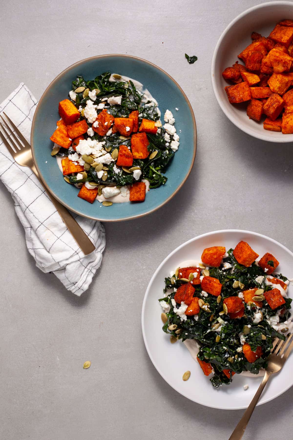 A serving of butternut squash and feta salad on a blue plate and a white plate.