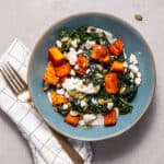 A serving of butternut squash and feta salad in a blue plate.