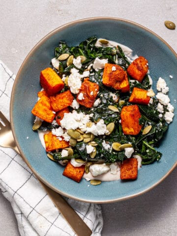 A serving of butternut squash and feta salad in a blue plate.