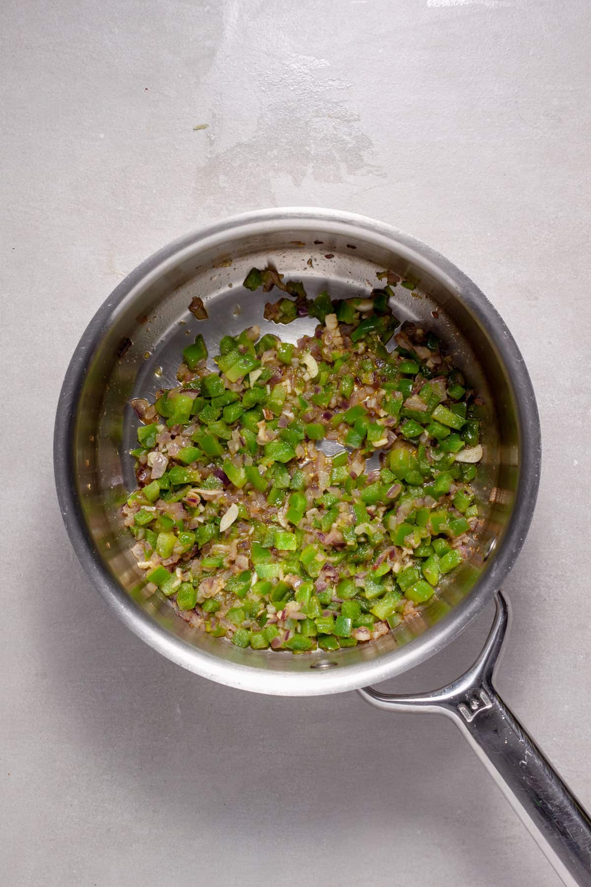 Peppers, onions and garlic cooking in a saucepan for tomato rice.