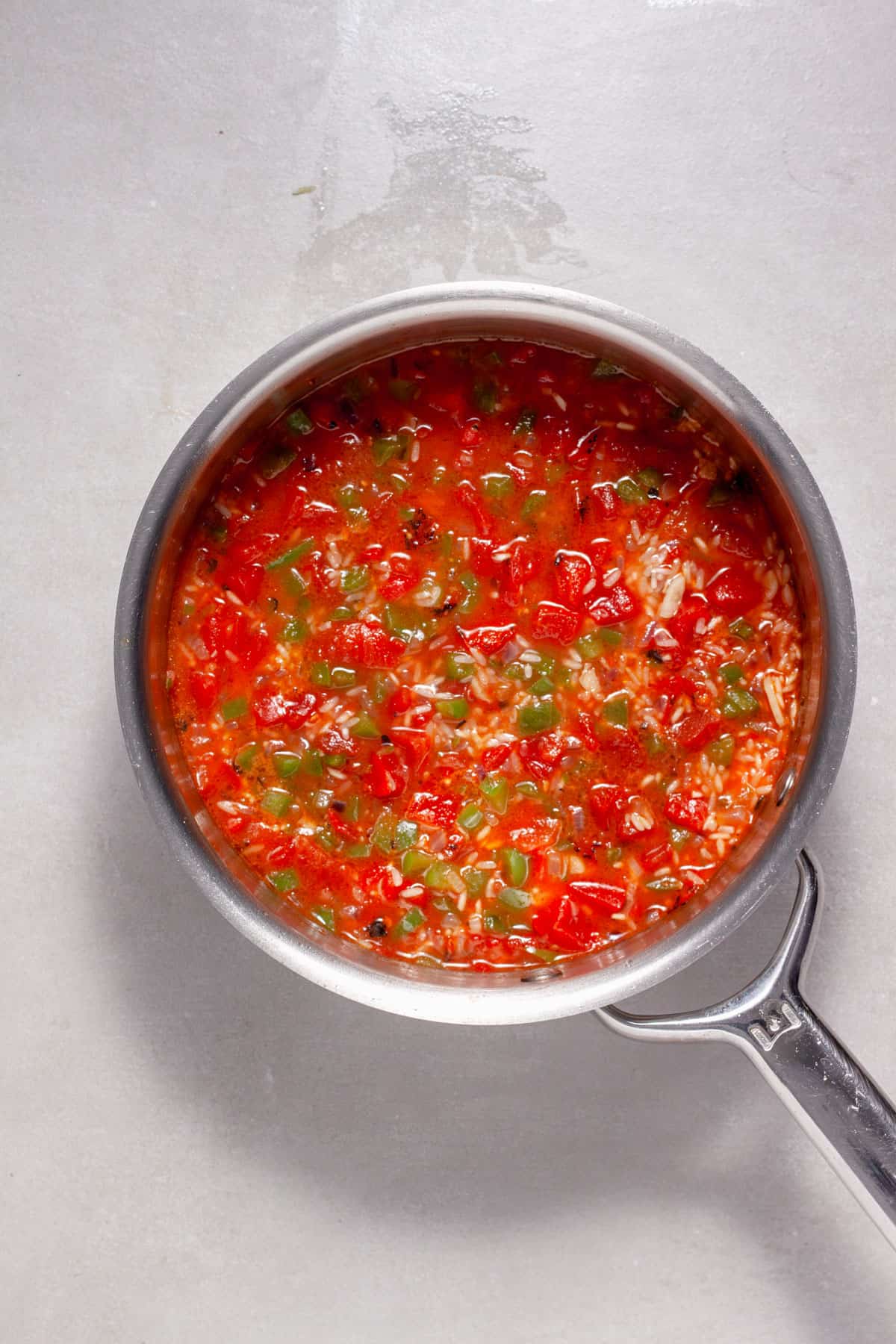 Tomato rice getting cooked in a saucepan.
