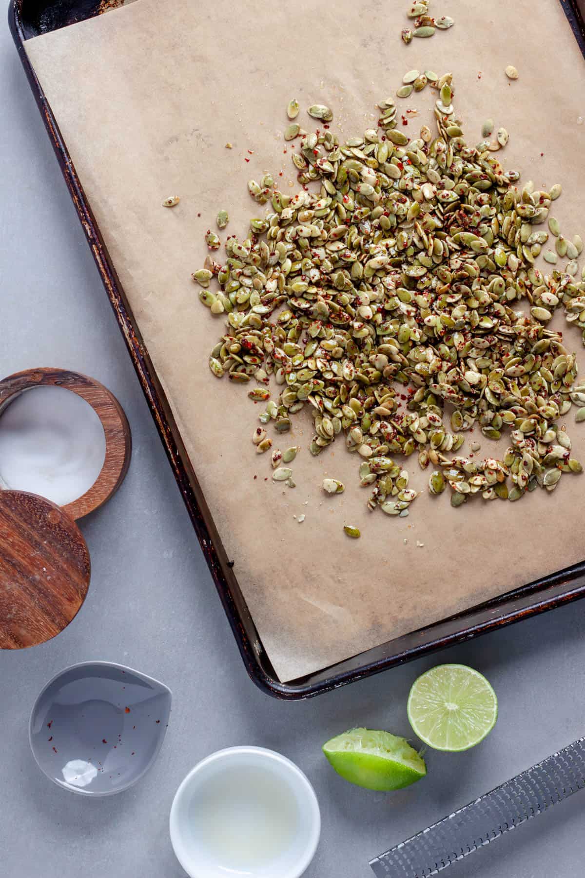 Chili lime pepitas on a parchment lined baking sheet getting ready to be roasted.