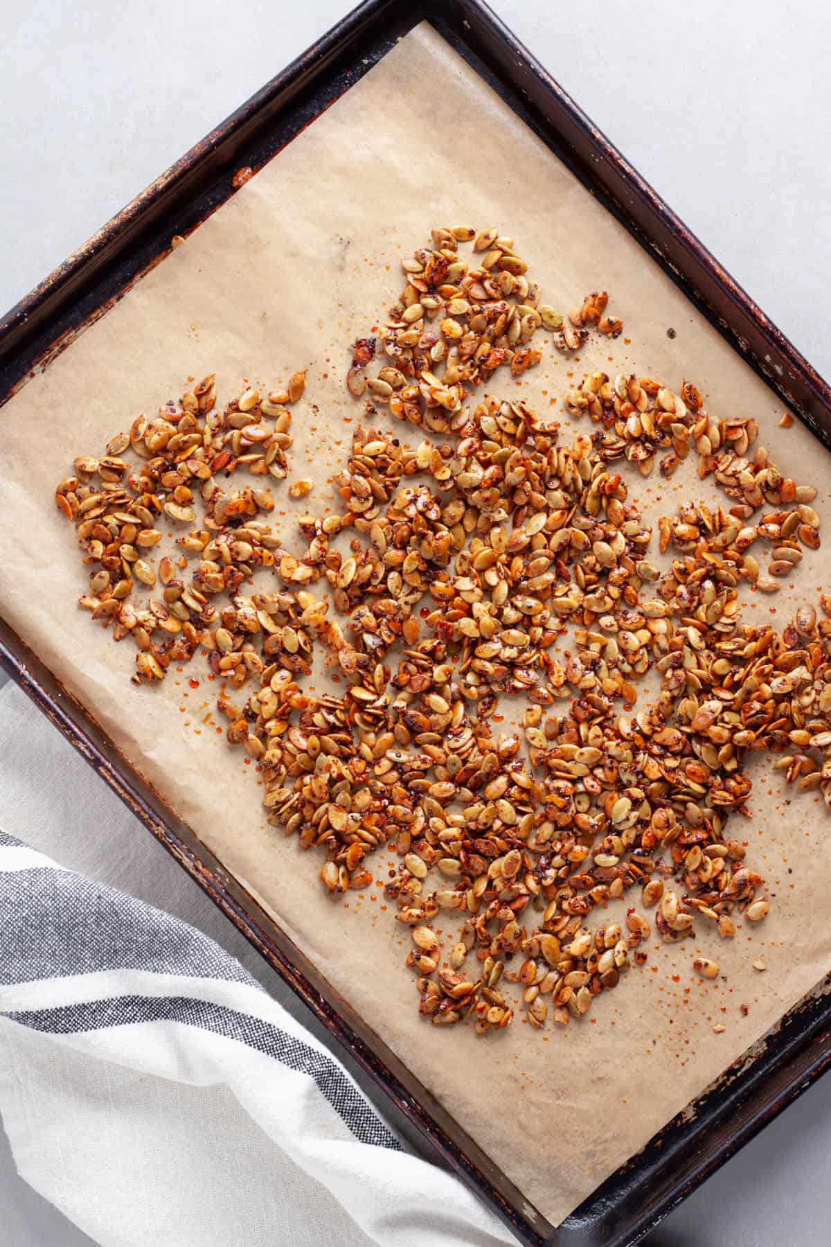 Roasted chili lime pepitas on a parchment lined baking sheet.