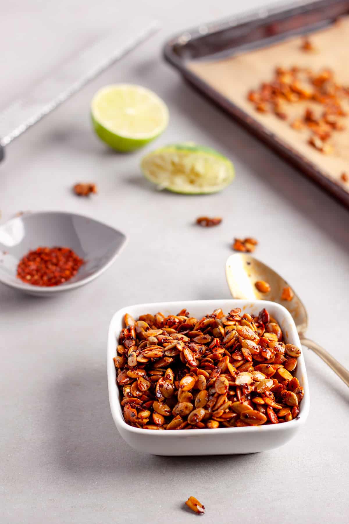 A small bowl of chili lime pepitas on a gray table.