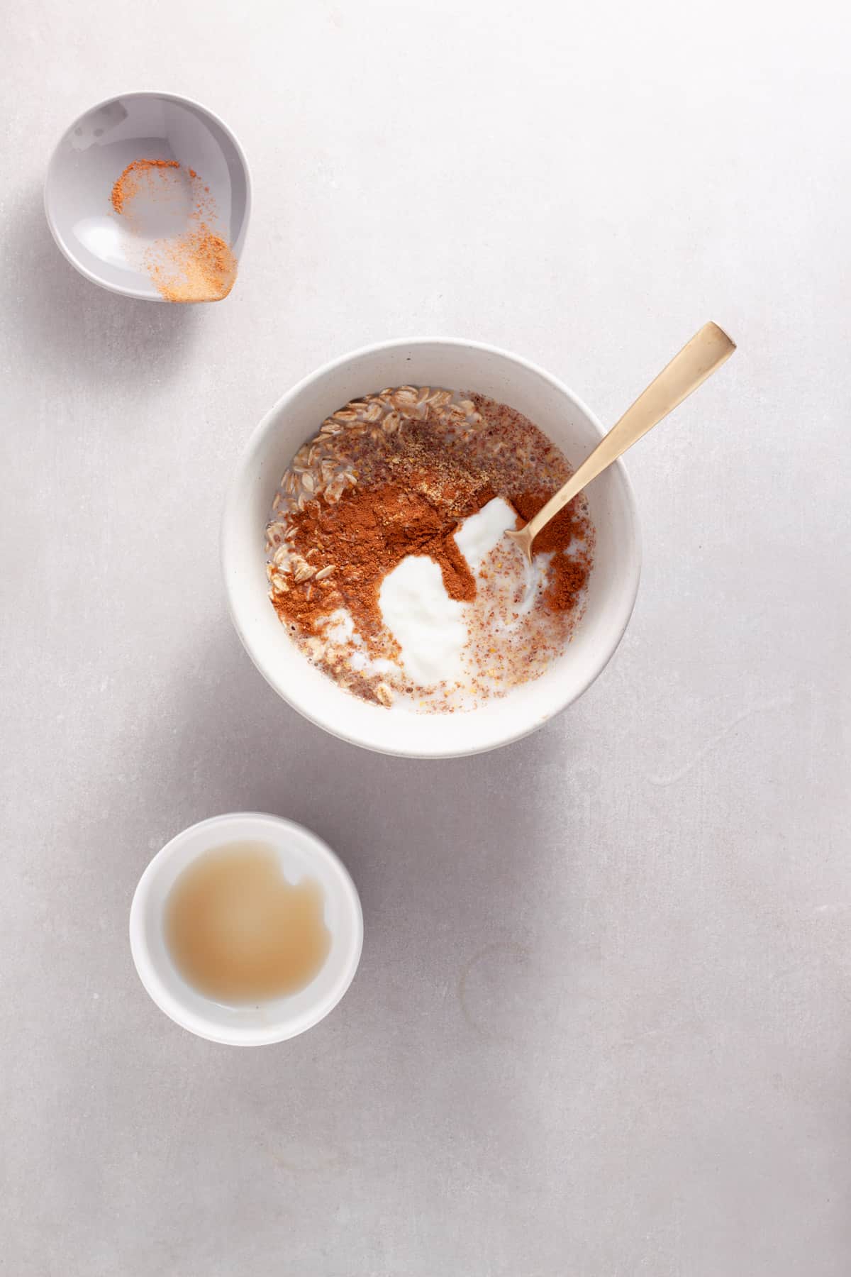 Ingredients for cinnamon overnight oats getting mixed in a medium bowl.