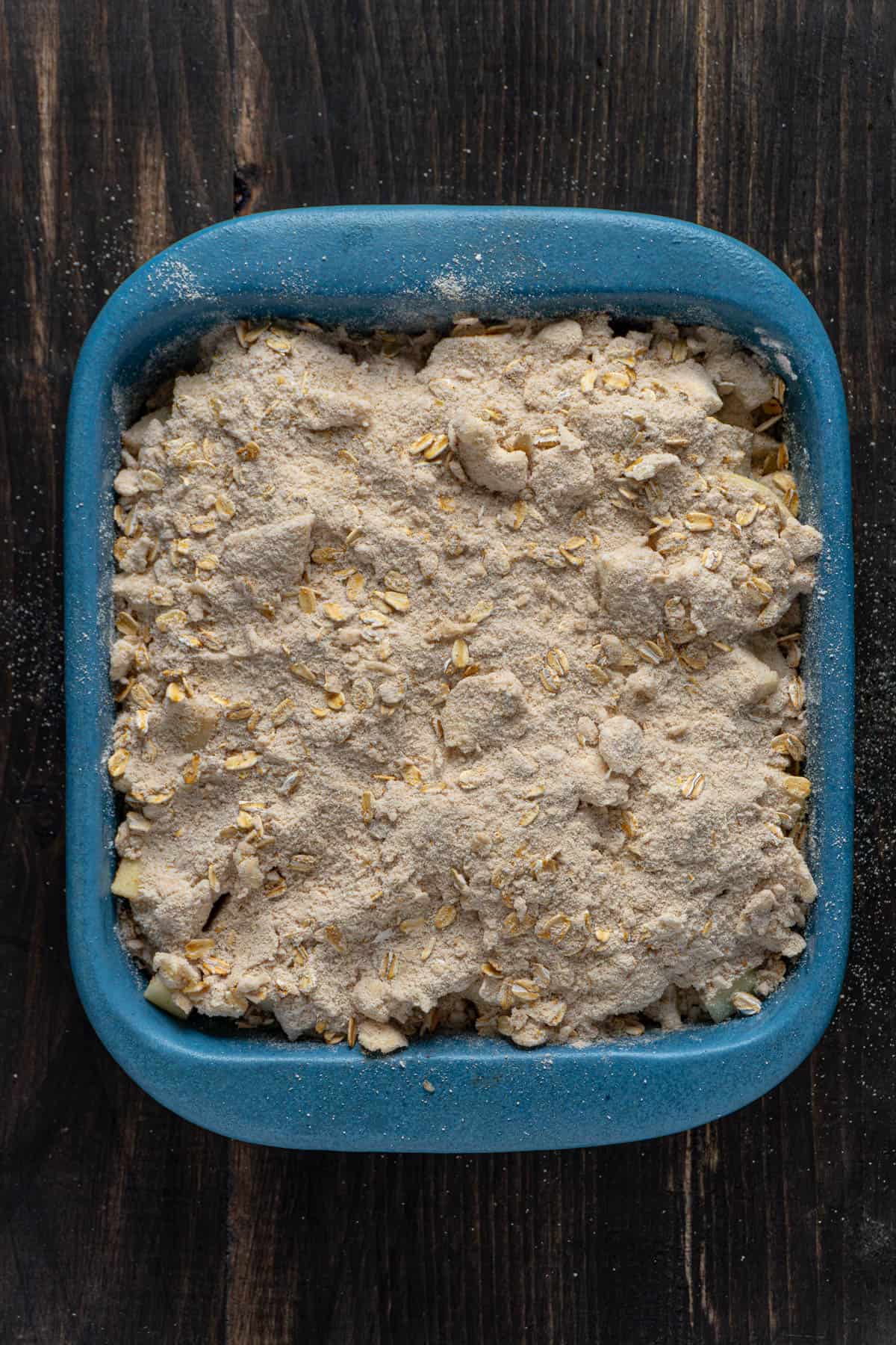 An uncooked gluten-free apple crisp in a blue baking dish.