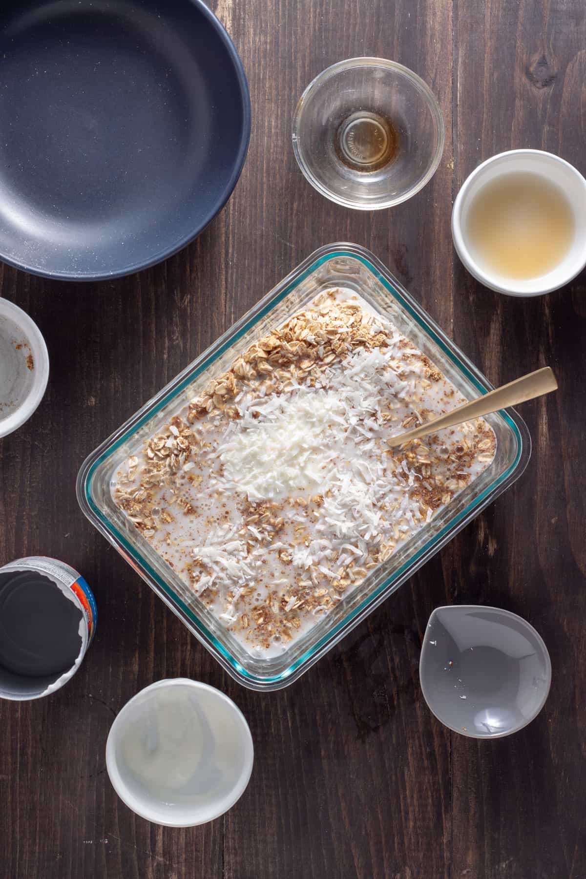 Overnight oats with coconut milk getting stirred together in a glass container.