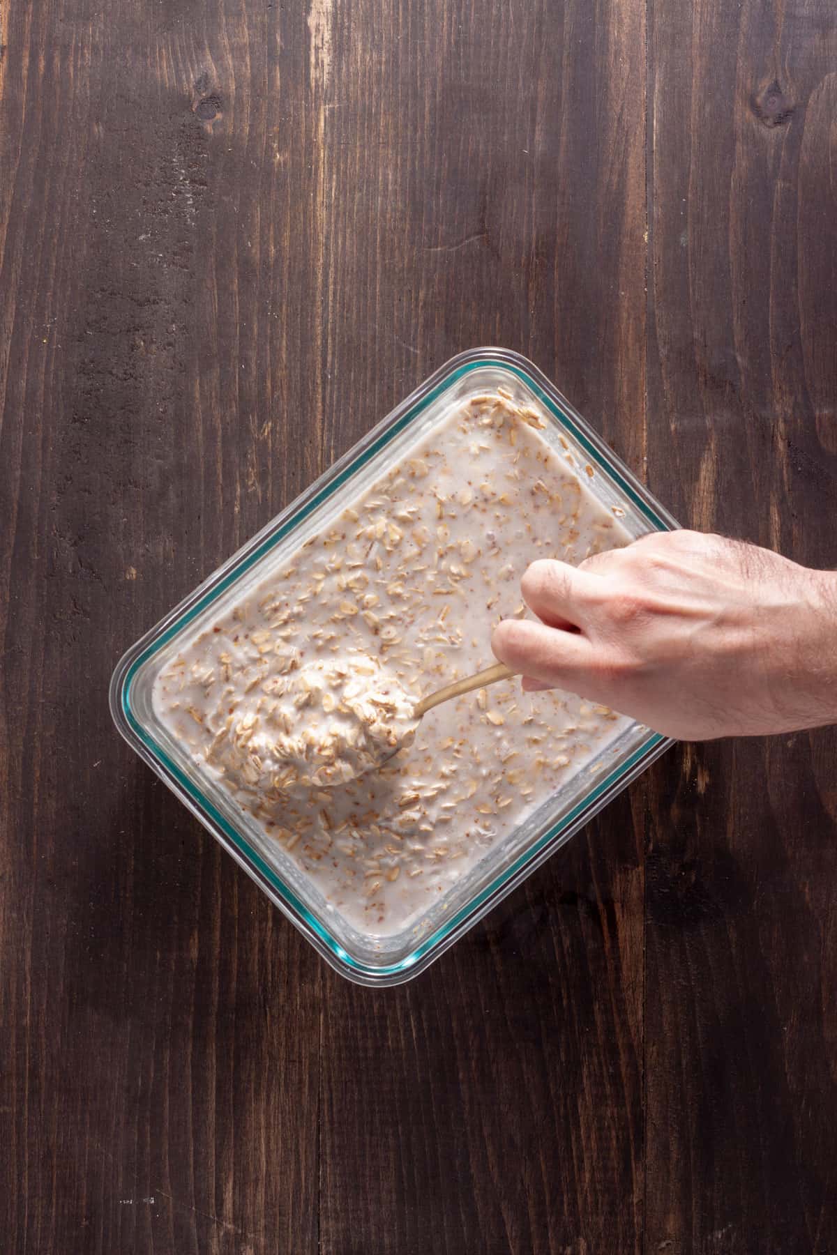 Overnight oats with coconut milk getting stirred together in a glass container.