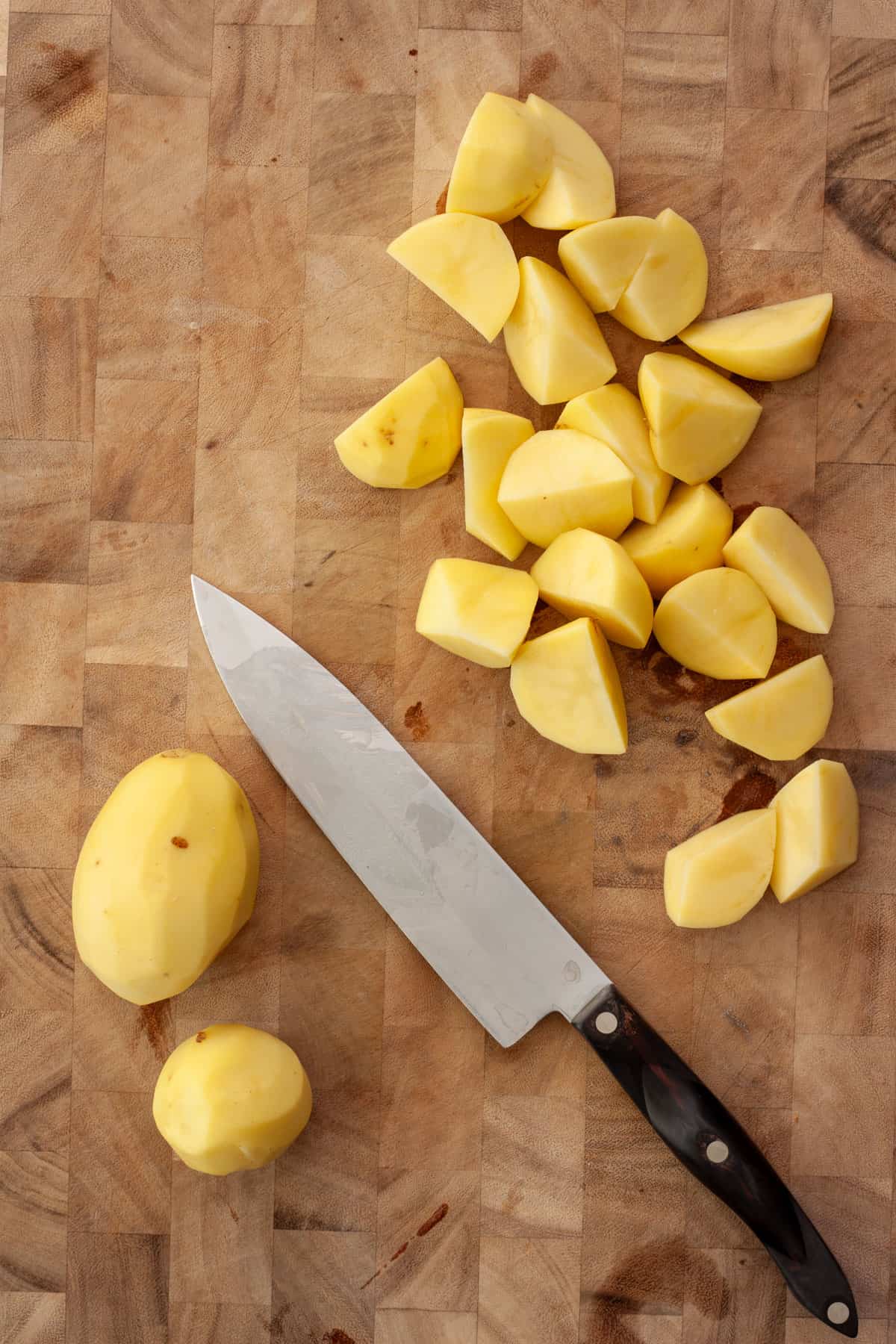 Peeled yukon gold potatoes getting cut before roasting.