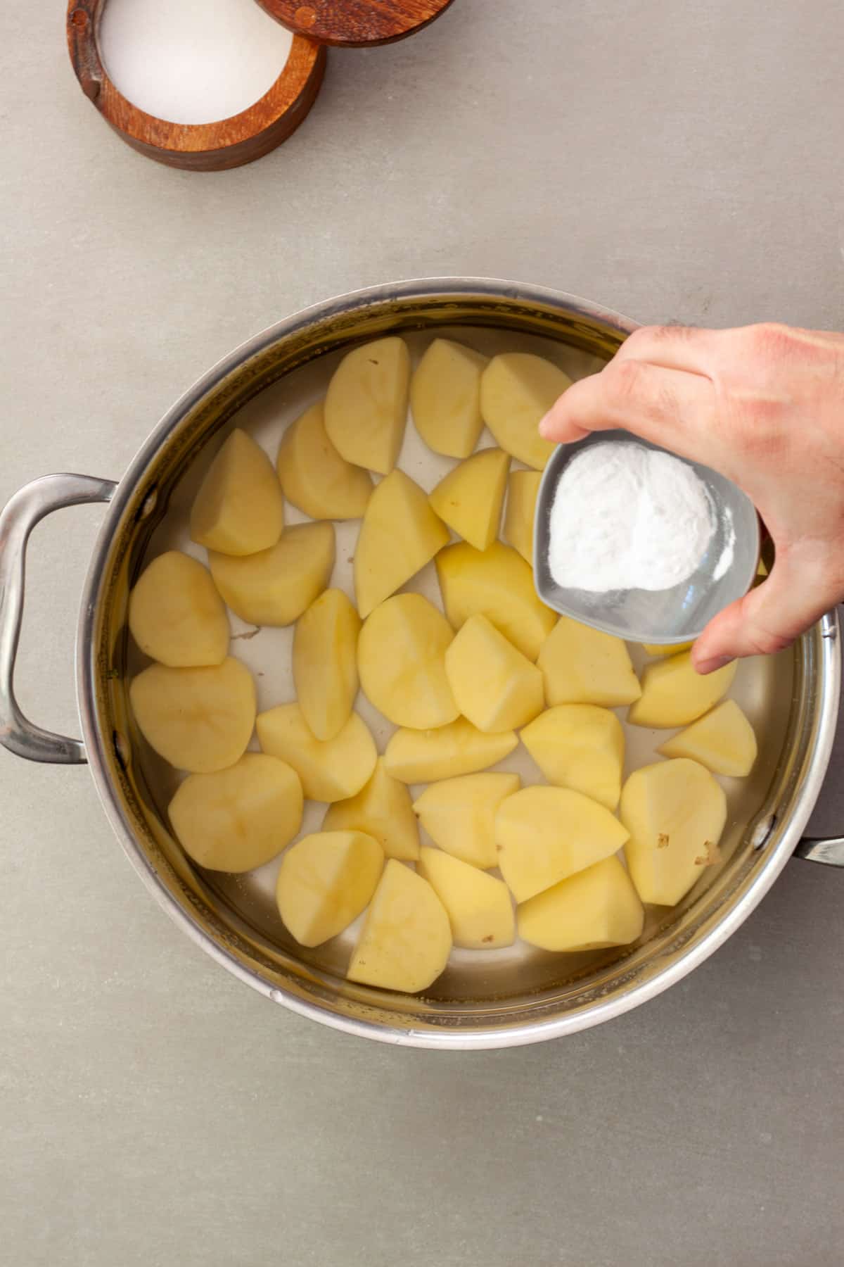 Chopped yukon gold potatoes in a pot of water with baking soda getting poured in.