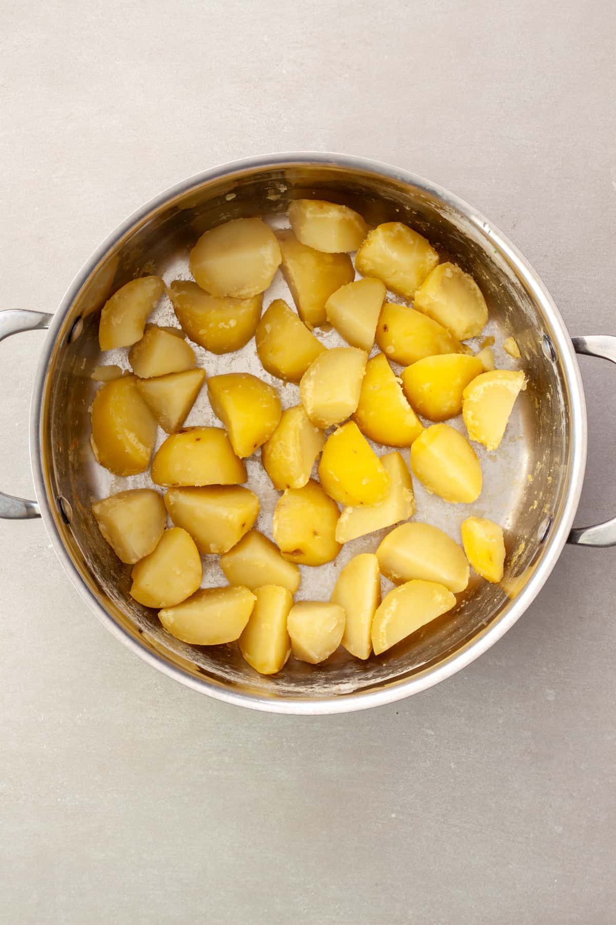 Partially cooked potatoes drained in a pot getting ready to be roasted.