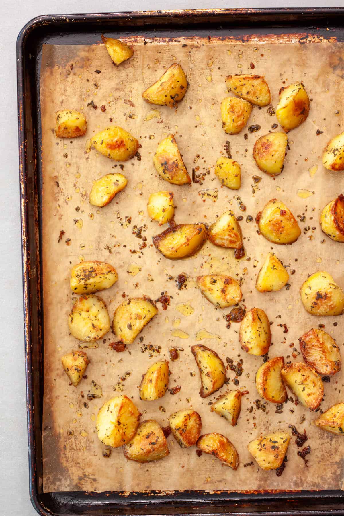 Crispy herb roasted yukon gold potatoes fresh out of the oven on a parchment lined baking sheet.