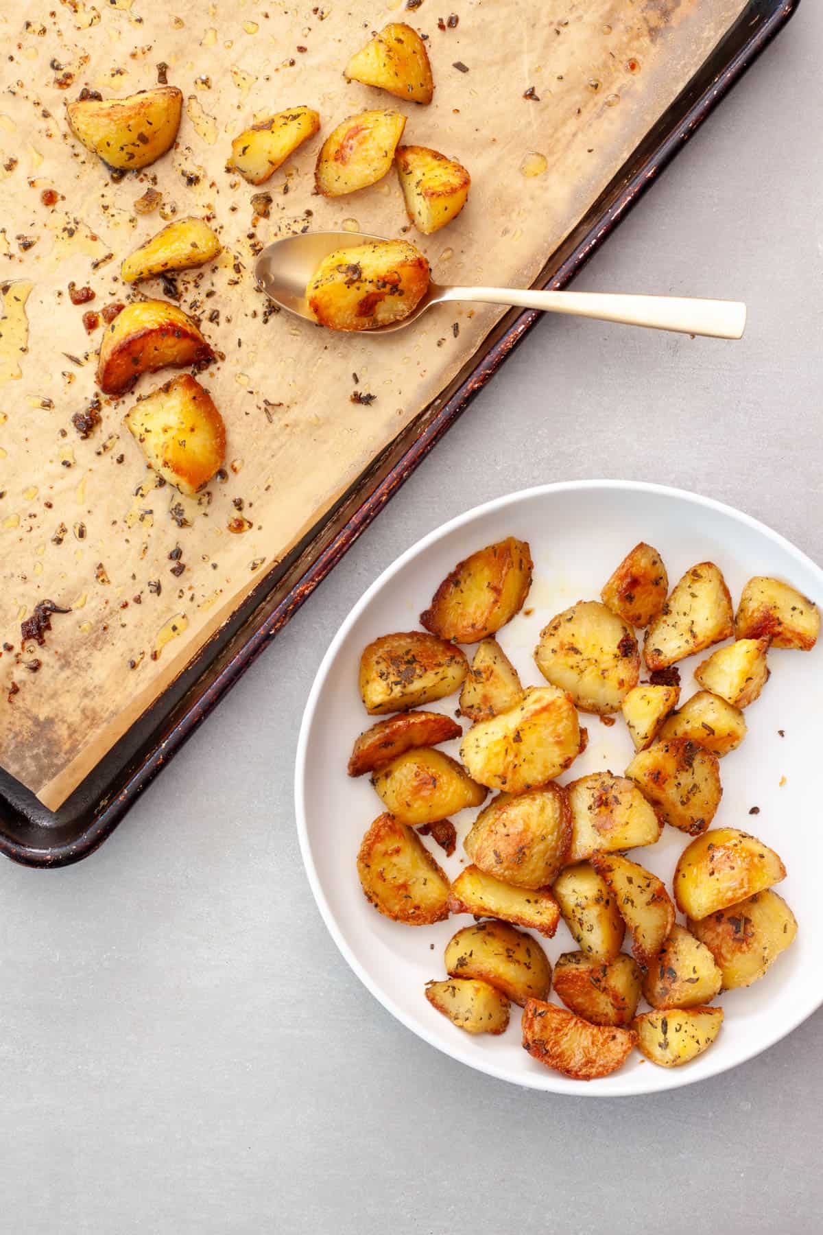 Crispy herb roasted potatoes getting transferred to a serving bowl.