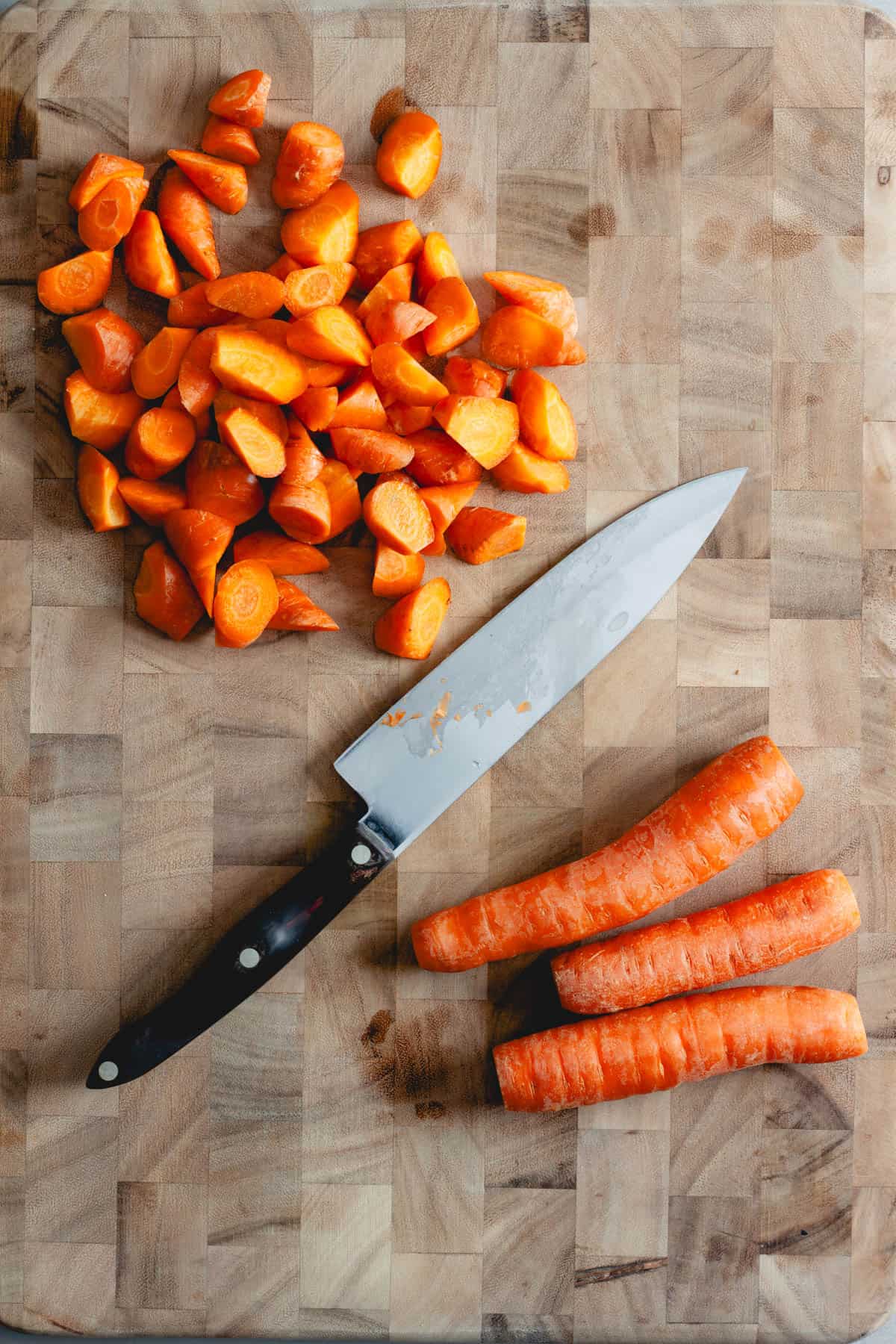 Carrots on a cutting board ready to get cut into oblong pieces.