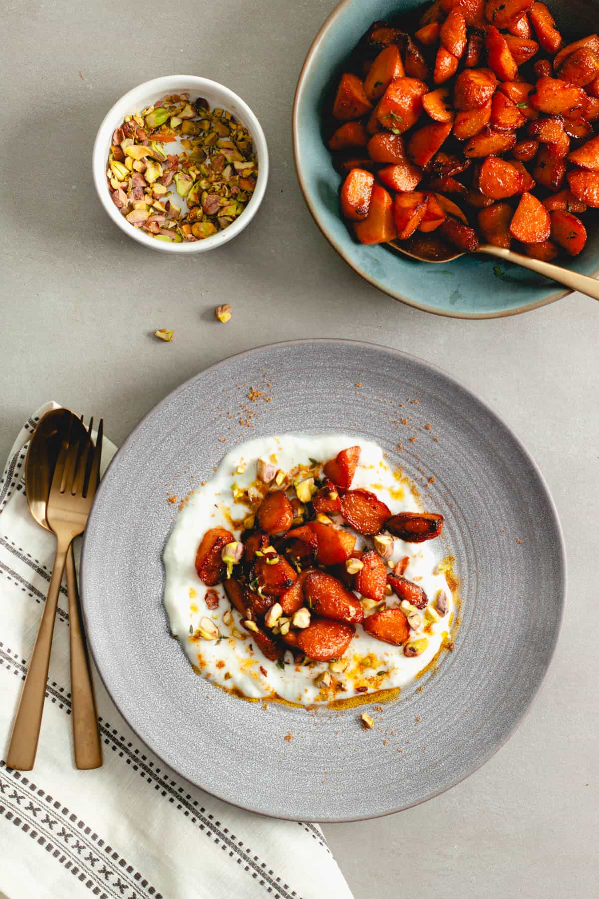 A bowl of yogurt topped with sauteed spiced carrots and pistachios.
