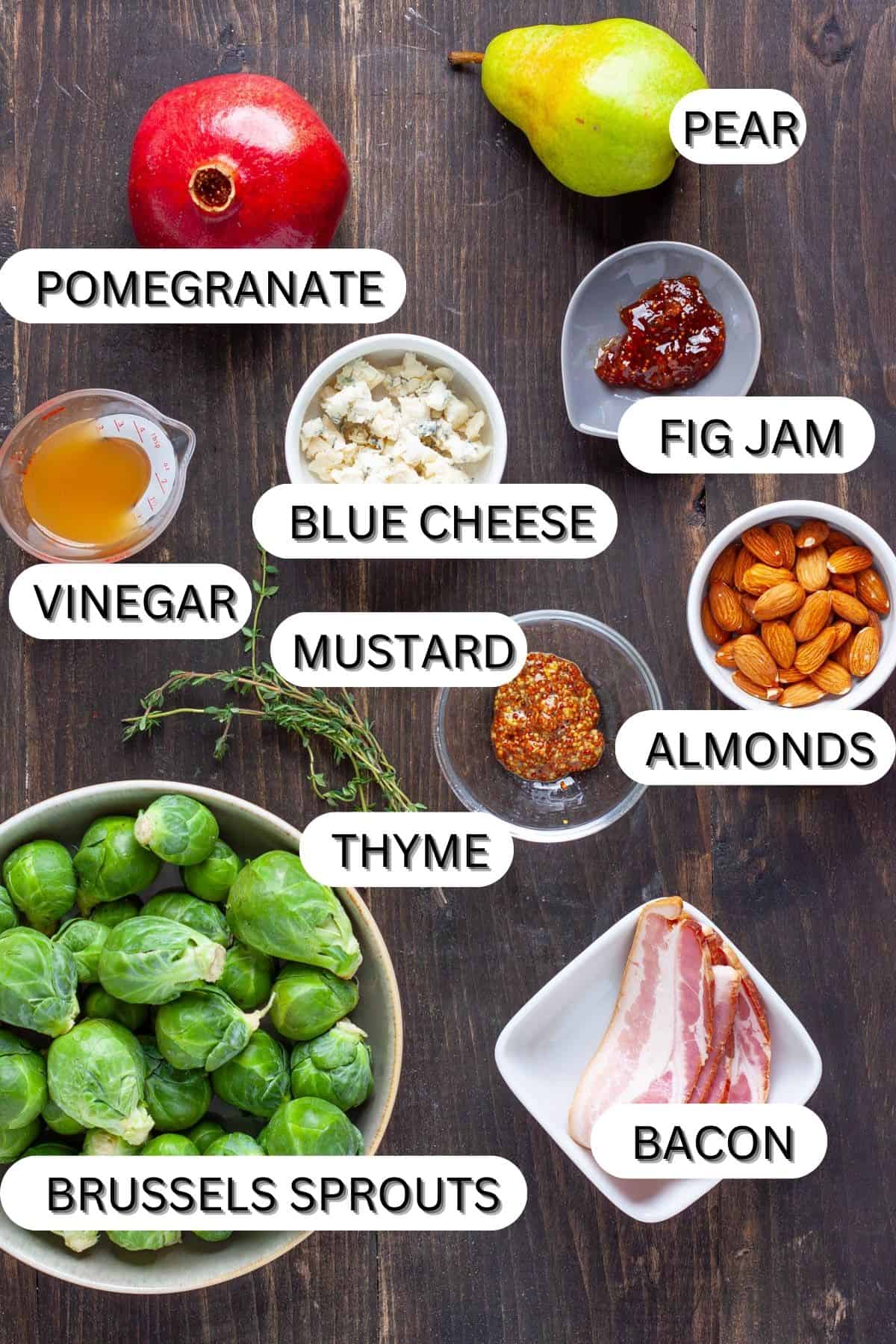 Ingredients for a brussels sprouts salad with bacon and fig dressing on a dark table.